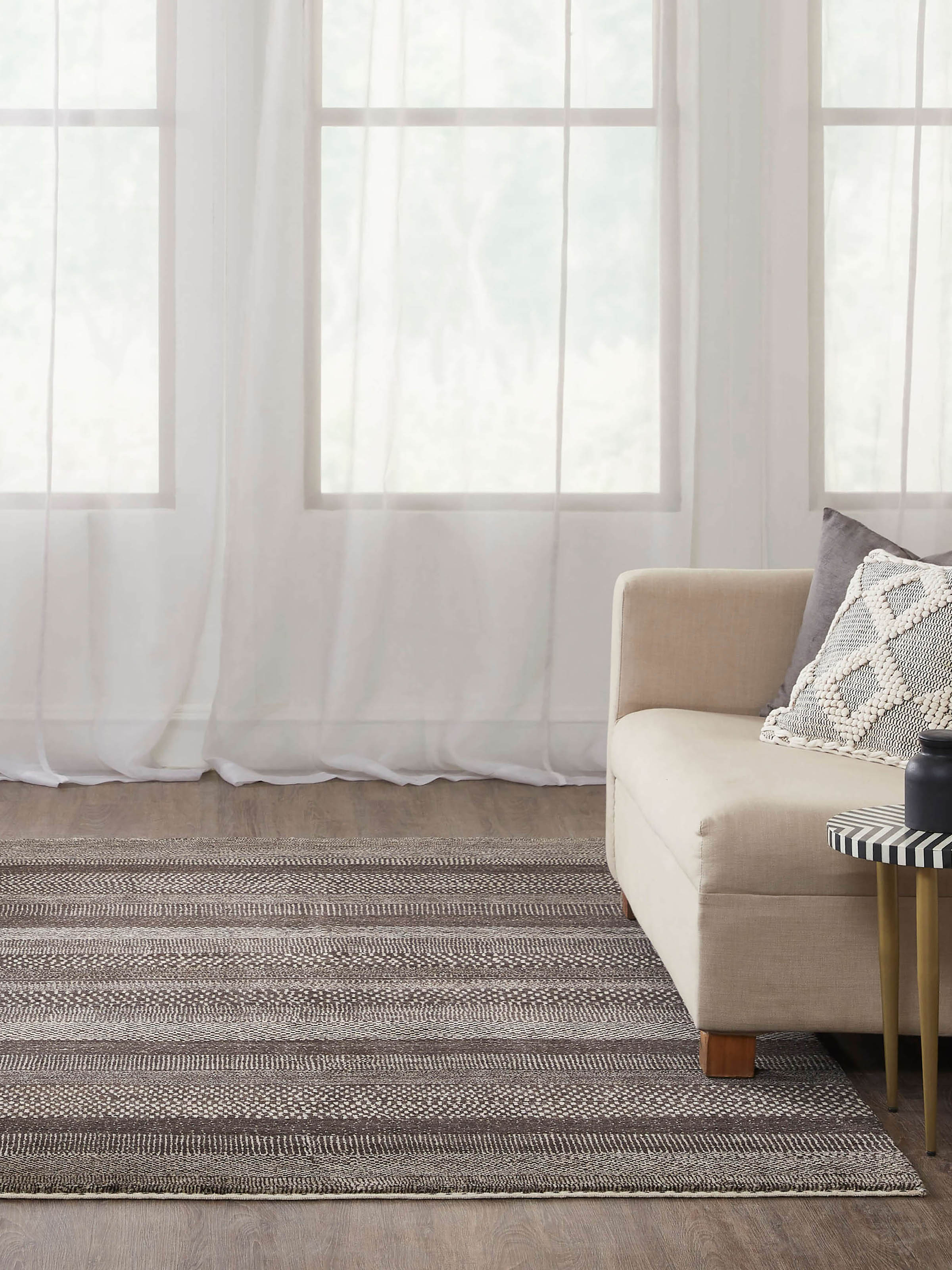 Lifestyle image of Gabbeh-style grey, brown, and charcoal Bhadohi wool rug, hand-knotted with tribal-inspired pattern.