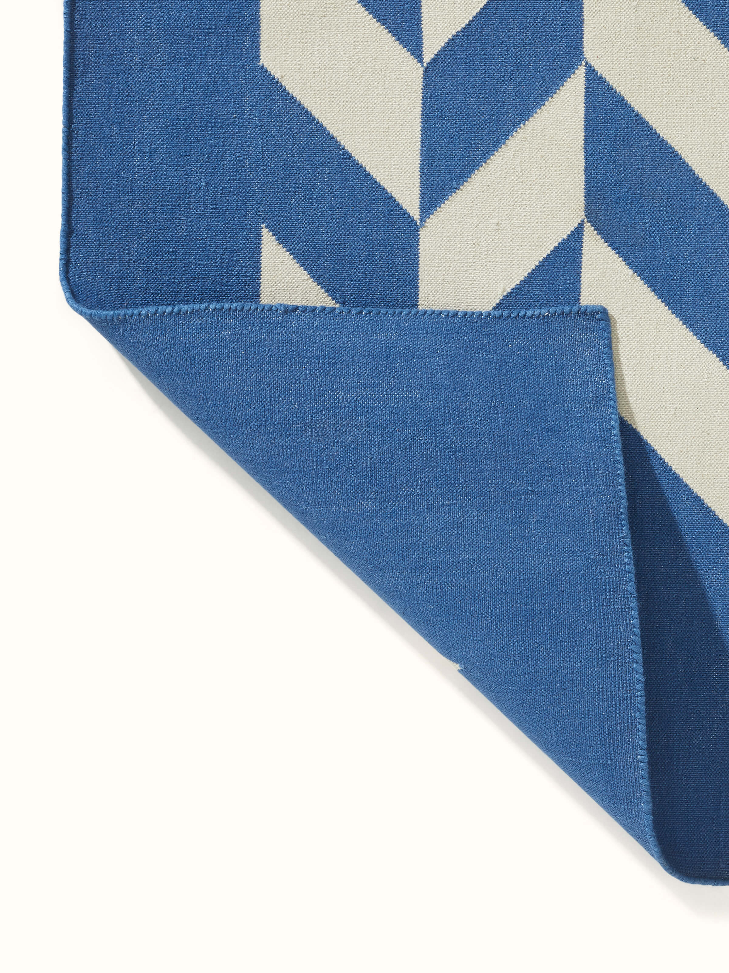 Close-up of Modern geo chevron blue ivory Lawan cotton Panja dhurrie, emphasizing the chevron design and fabric texture