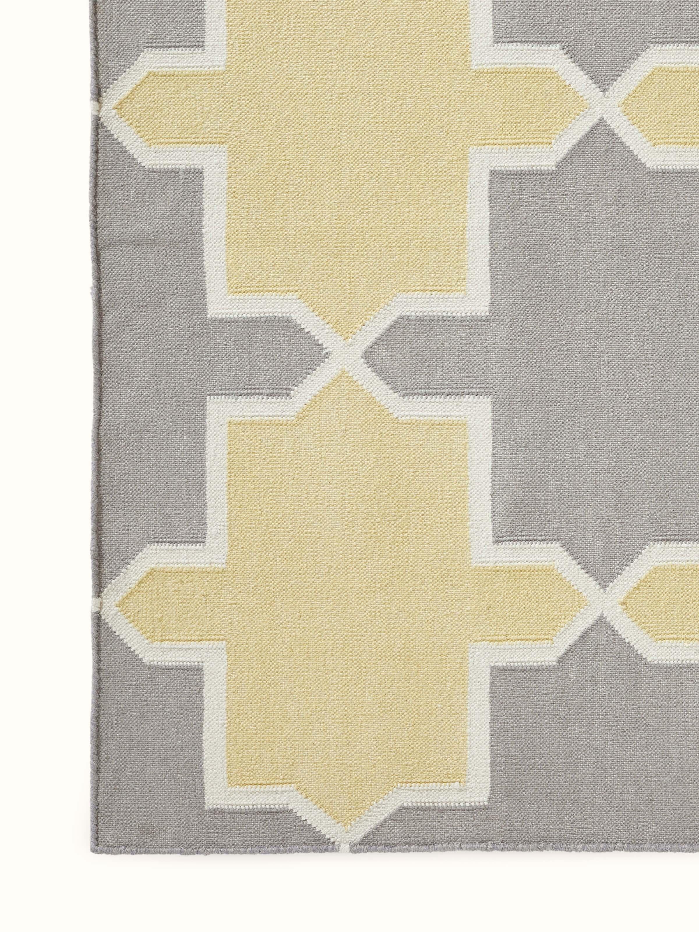 Side view of Modern Geo grey yellow Lawan cotton panja dhurrie showing the thickness and edge design