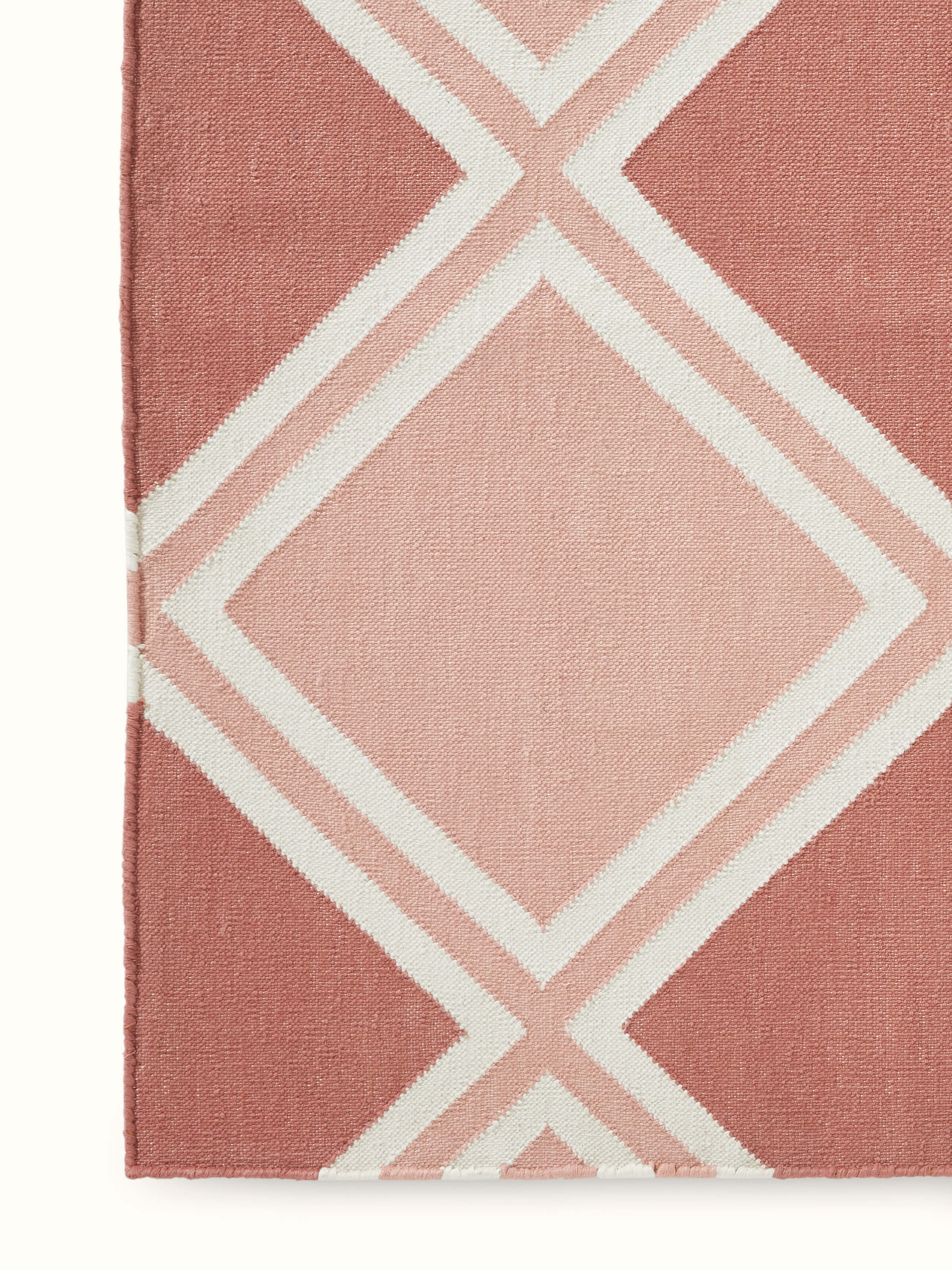 Angled view of Modern geo diamond red blush lawan cotton panja dhurrie displaying its full design and layout.