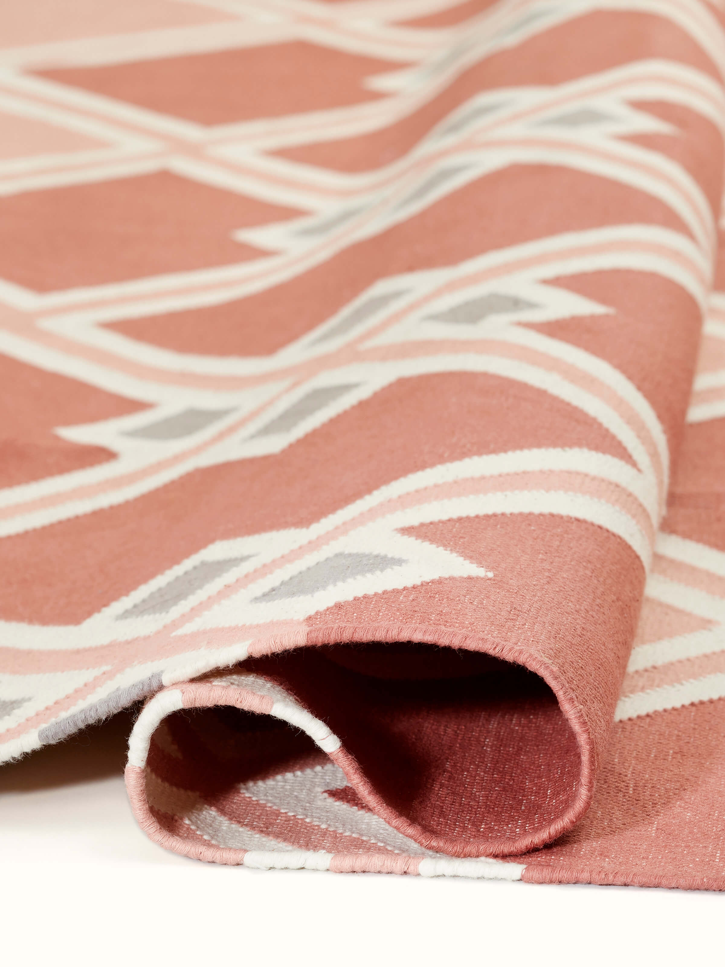 Close-up view of Modern geo diamond red blush lawan cotton panja dhurrie focusing on the fabric texture and pattern.