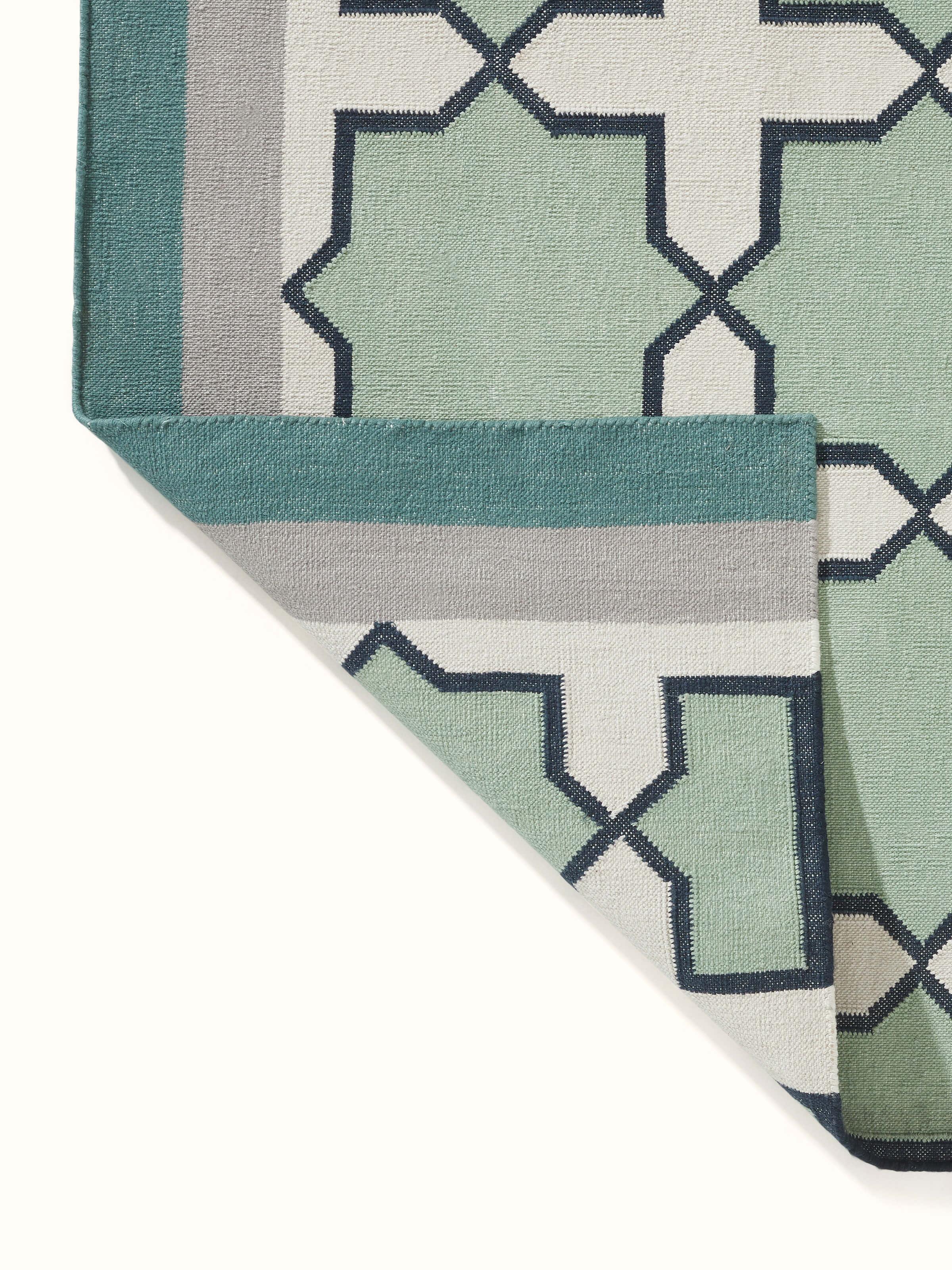 Full view of Modern Geo Jharokha green grey Lawan cotton Panja dhurrie laid out, demonstrating its size and overall design in a room setting