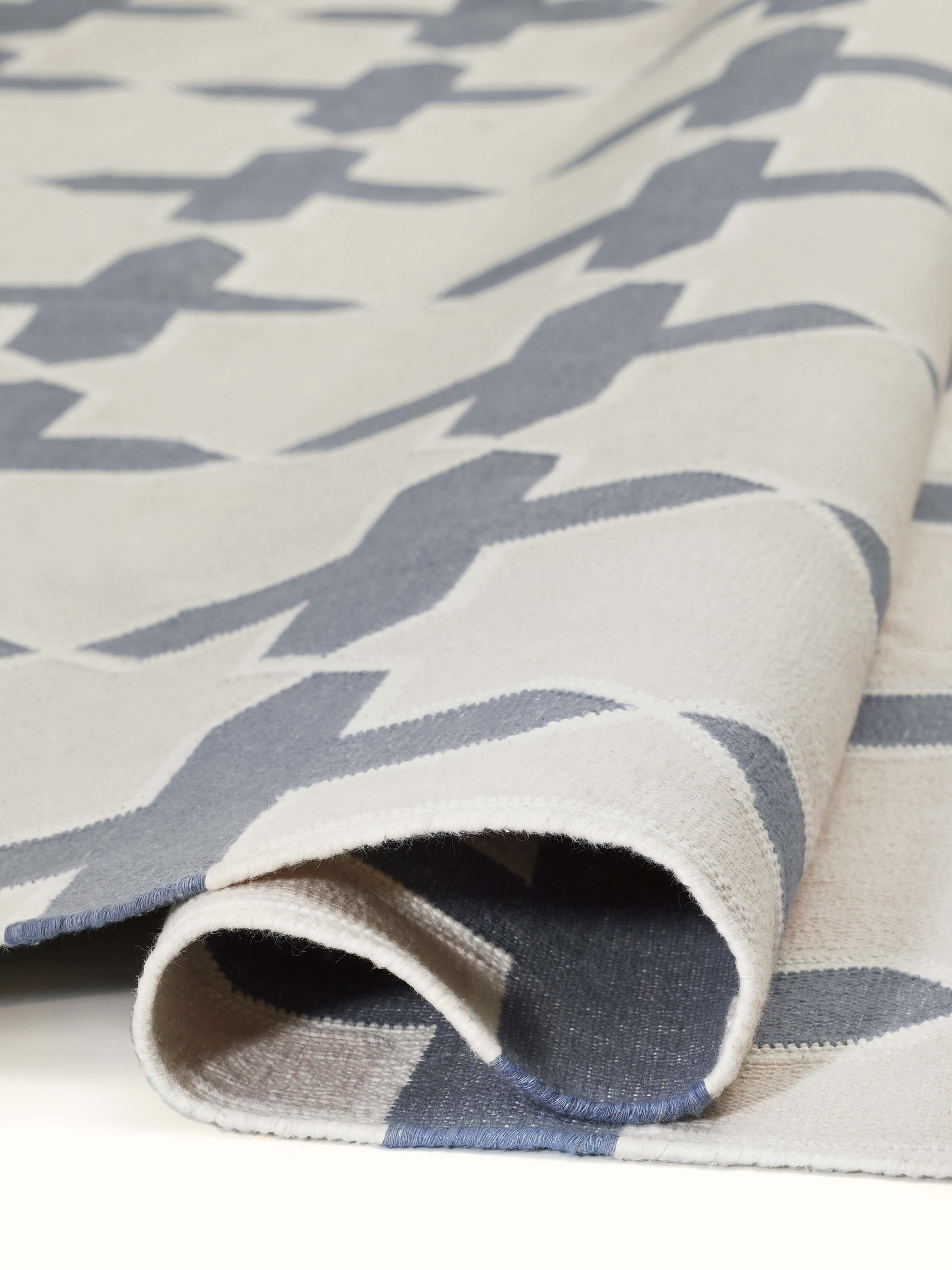 Modern geo jharokha grey blue lawan cotton panja dhurrie displayed on the floor, highlighting its size and design.