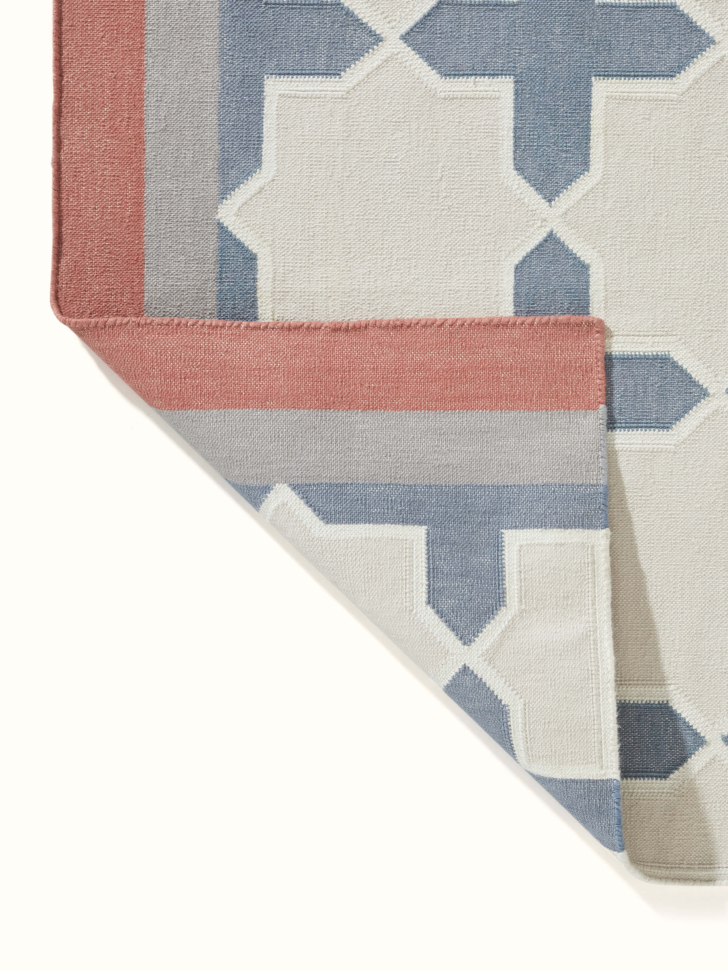 Modern geo jharokha grey blue lawan cotton panja dhurrie rolled up to show the design details and fabric.