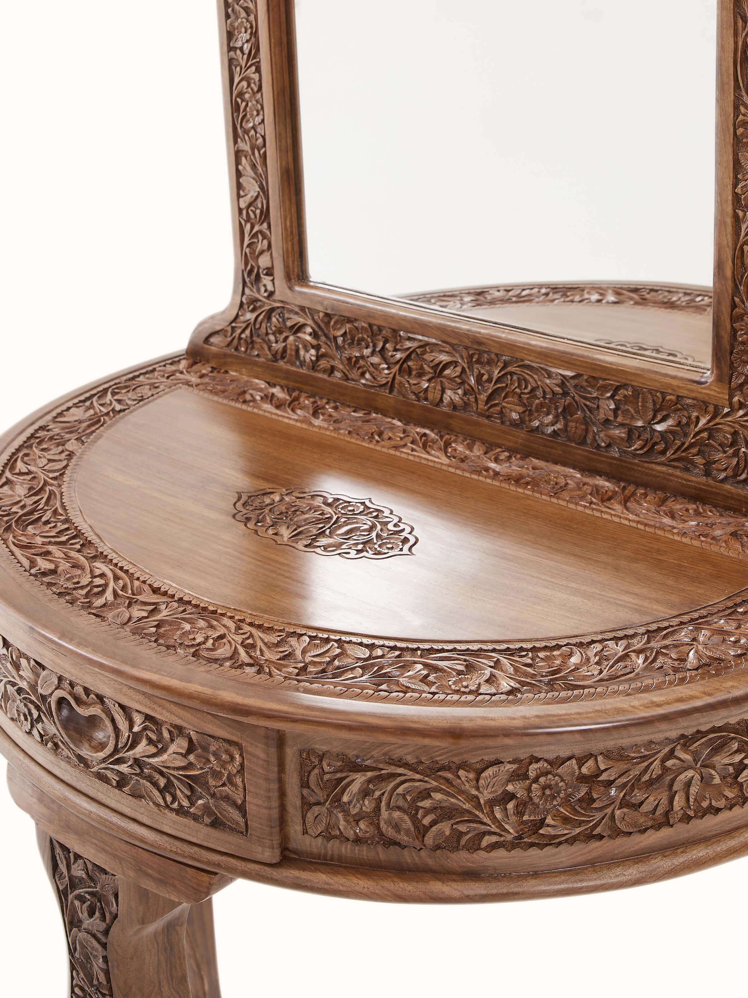 Close-up of the carved walnut wood and glass dressing table, capturing the fine details of the carvings and glass top