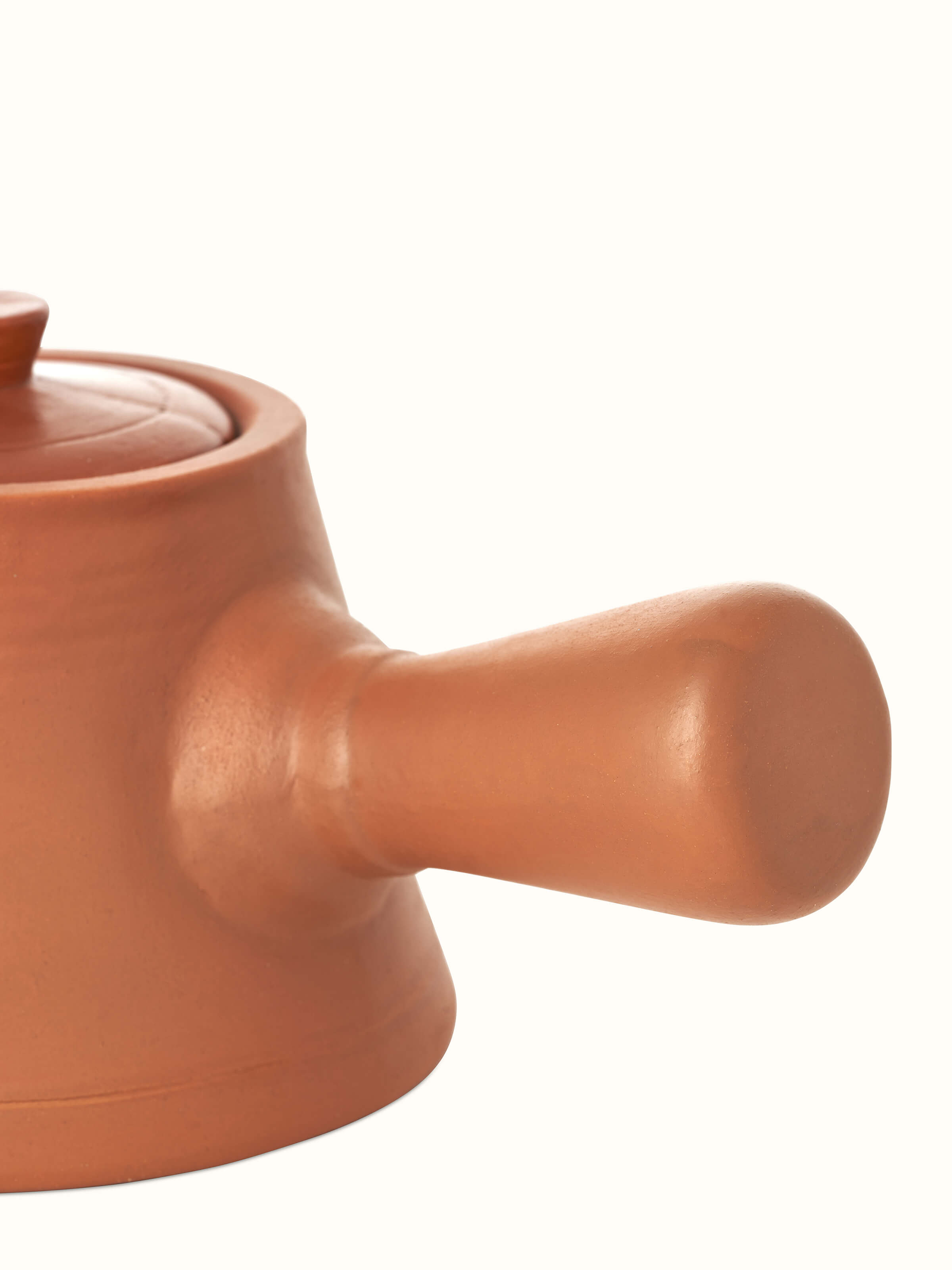 Close-up of terracotta clay saucepan, focusing on the texture and traditional craftsmanship.