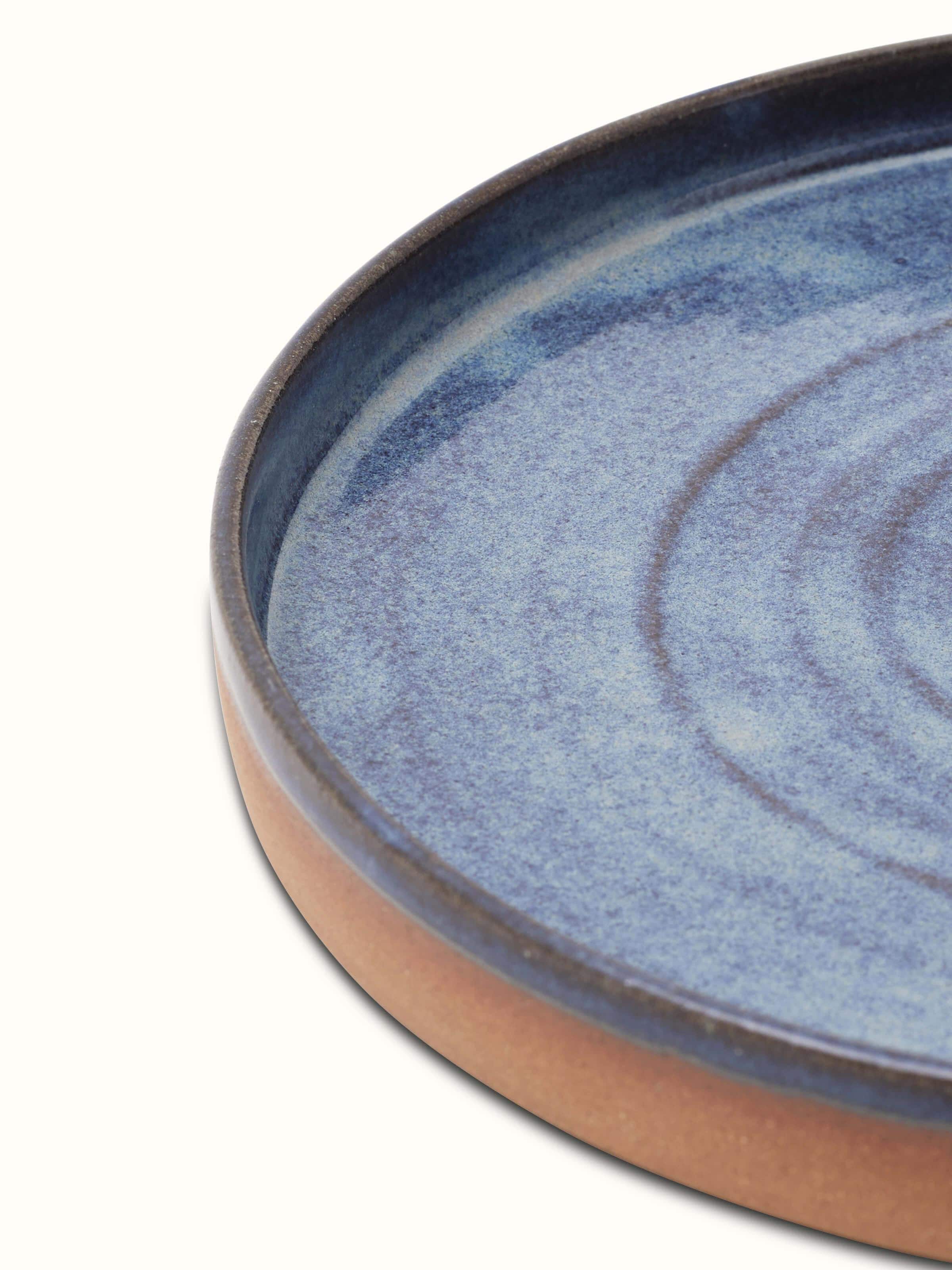 Close-up of studio pottery ceramic dinner plate blue focusing on the intricate glaze details.