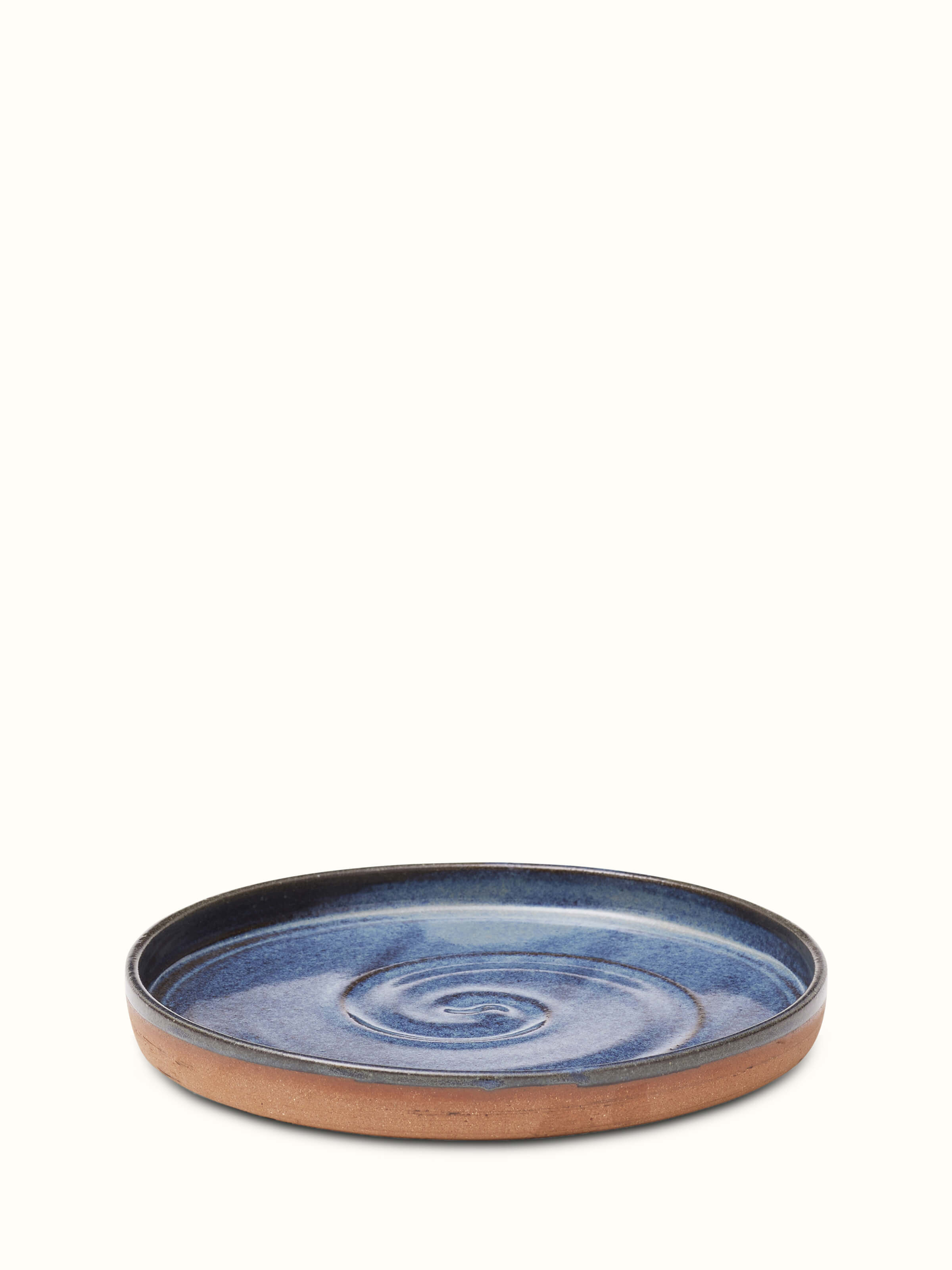 Side view of studio pottery ceramic blue dessert plate highlighting its curved edges and artisanal craftsmanship