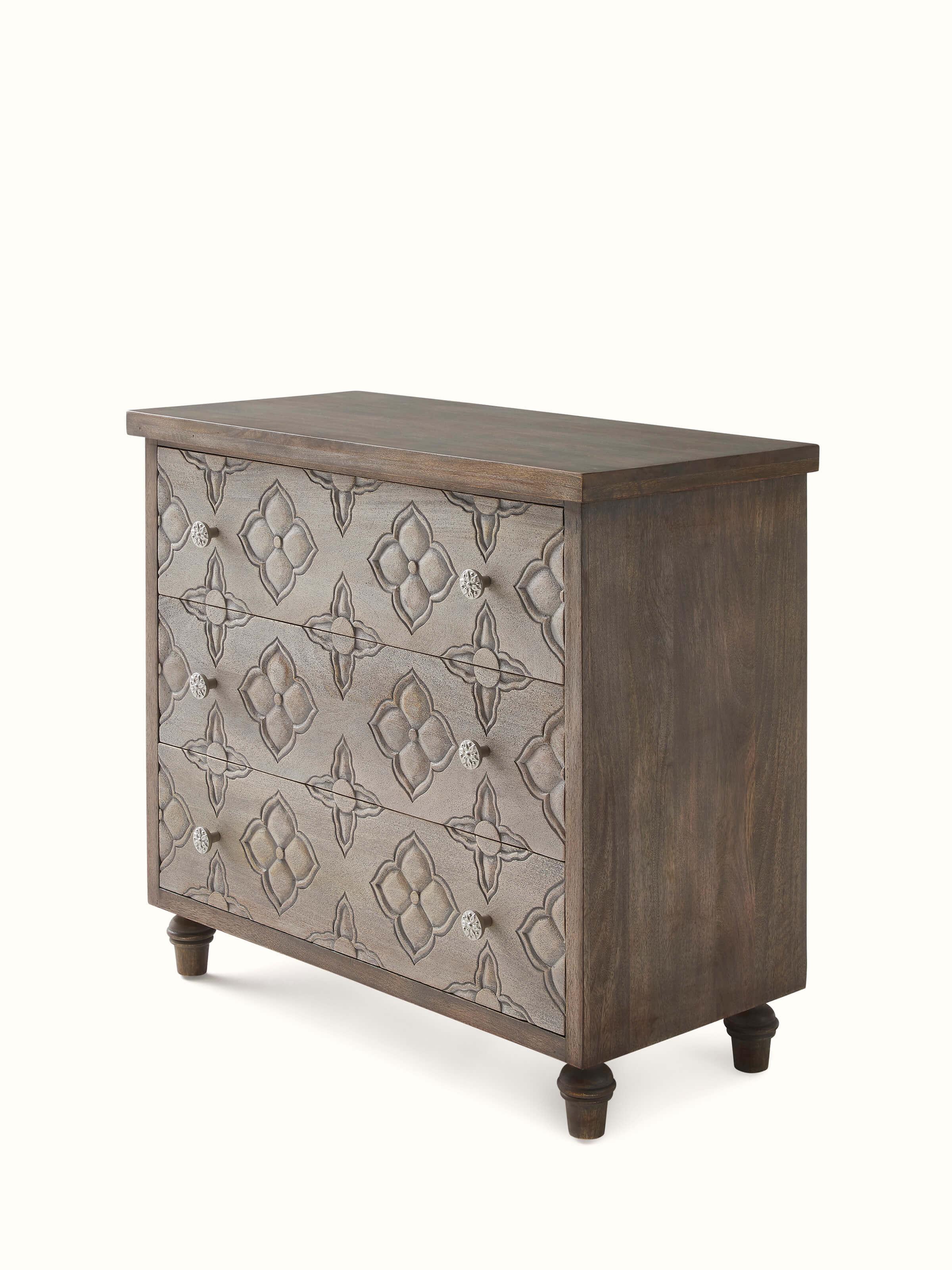 Close-up view of the carved details on the mango wood chest of drawers, focusing on the intricate patterns