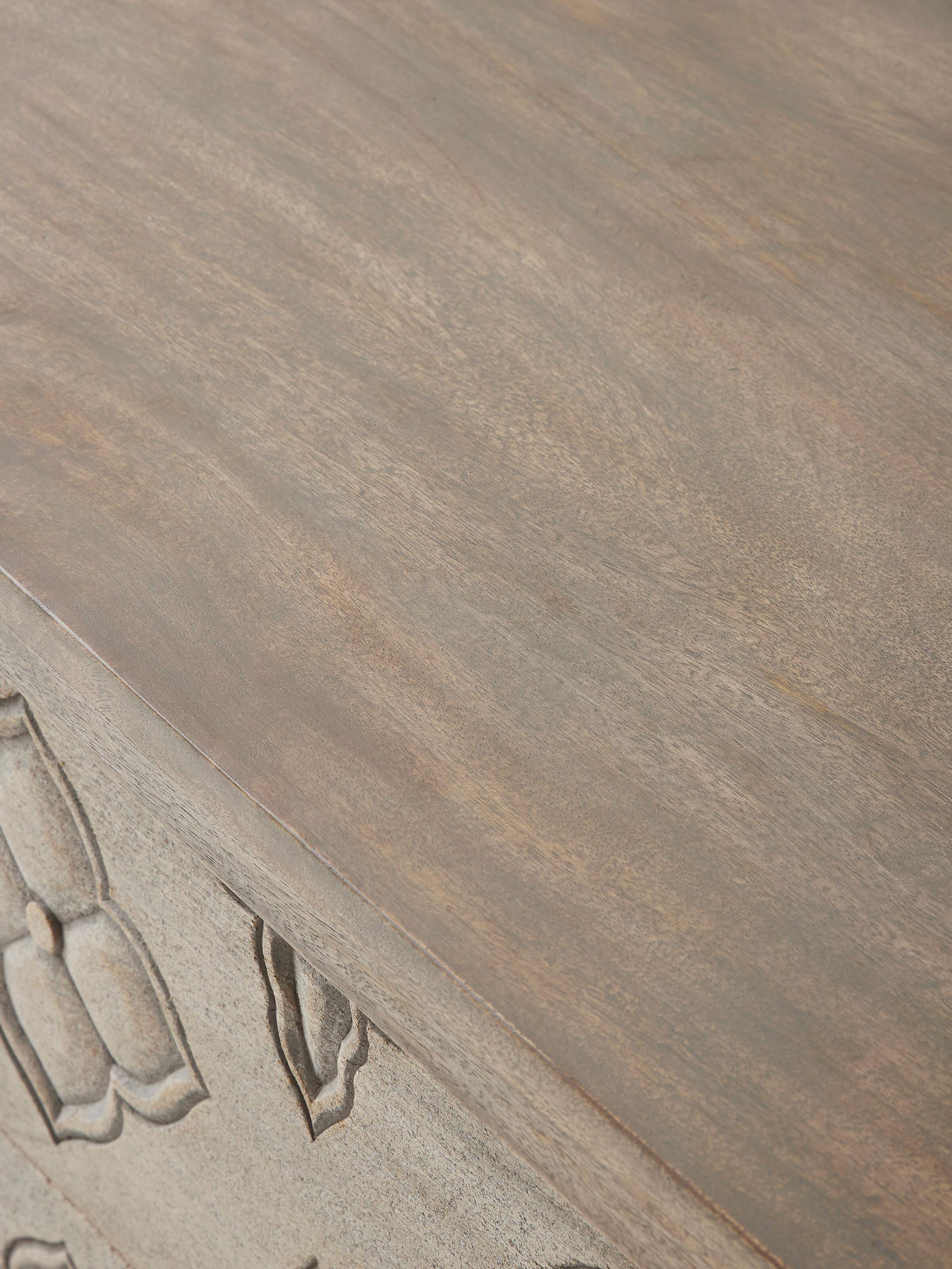 Close-up of the carved top of the mango wood chest of drawers, highlighting the craftsmanship and texture