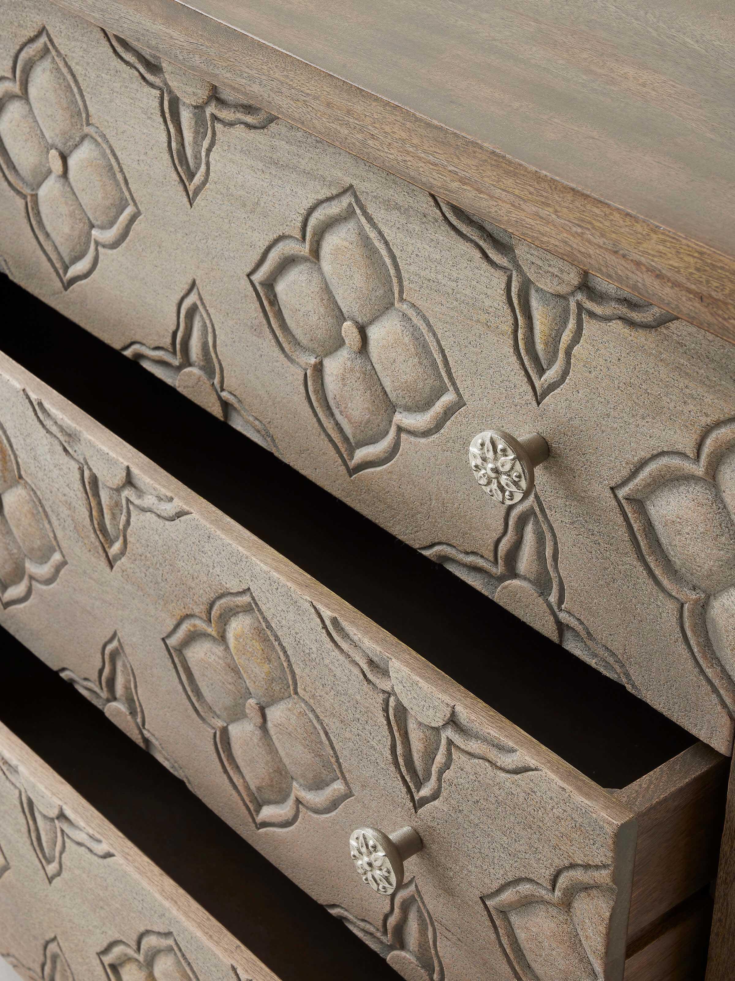 View of the chest's drawers and carved handles, showcasing the detailed design and functionality