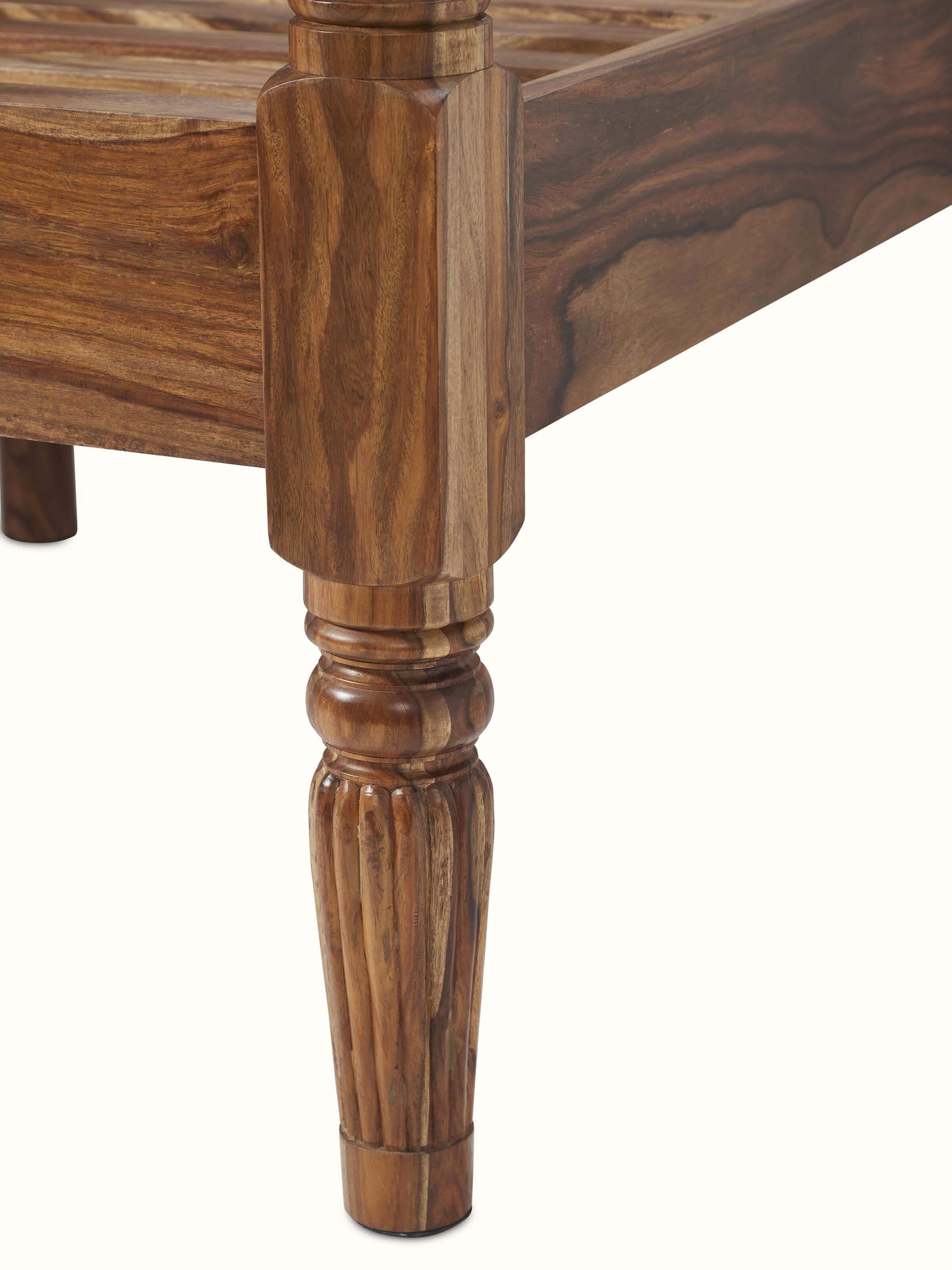 Close-up of the intricate carvings on the Sheesham wood poster bed, emphasizing the fine details.