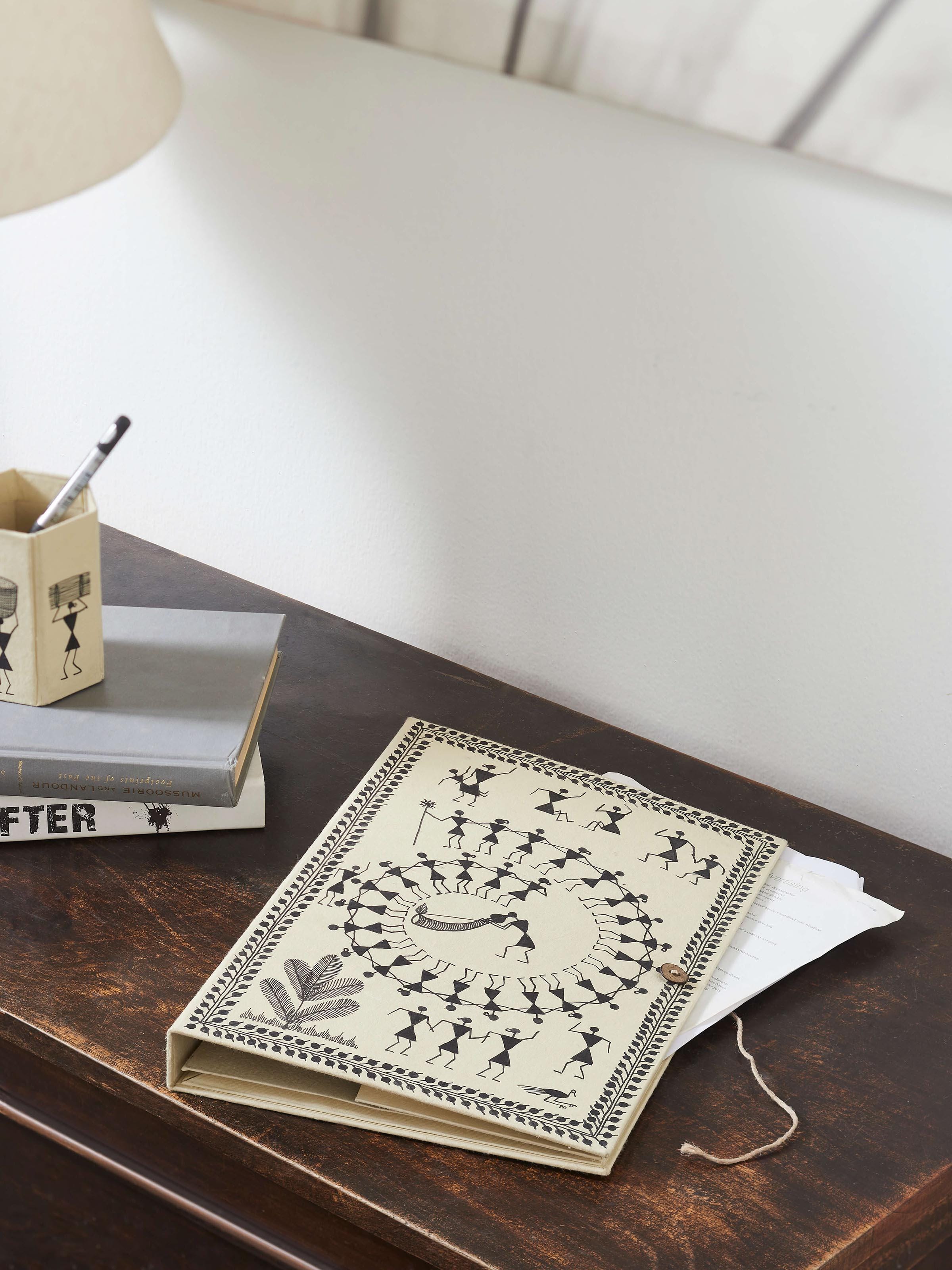 Close-up of Warli painted paper file folder in brown, highlighting Warli art patterns and color details