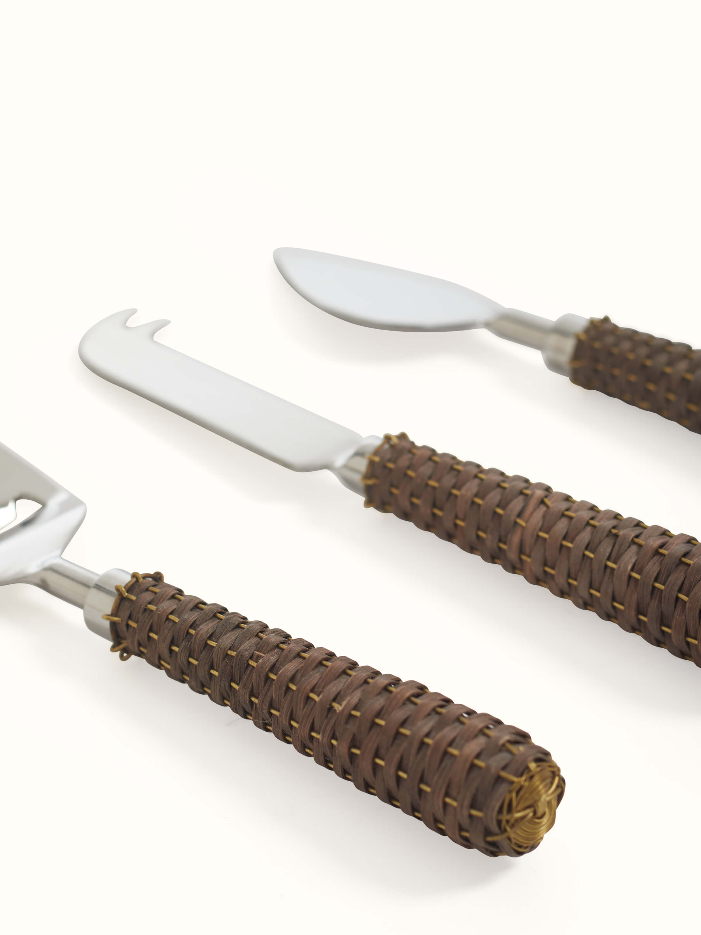 Full set of stainless steel cheese knives with rattan handles, highlighting the stylish and functional design.