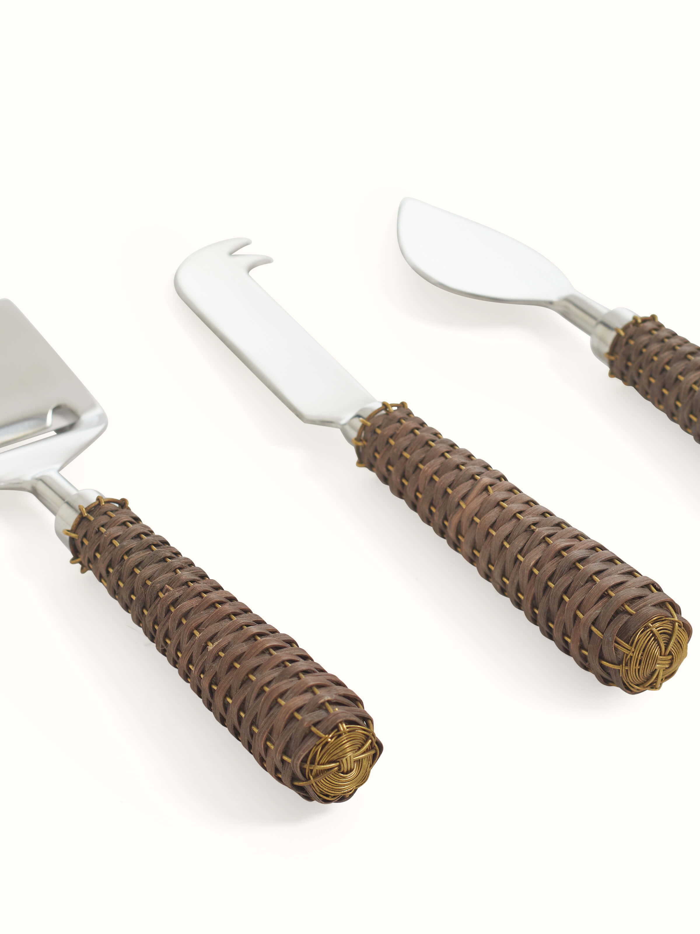 Detailed view of the rattan handles on the stainless steel cheese knives, emphasizing the textured grip and craftsmanship.