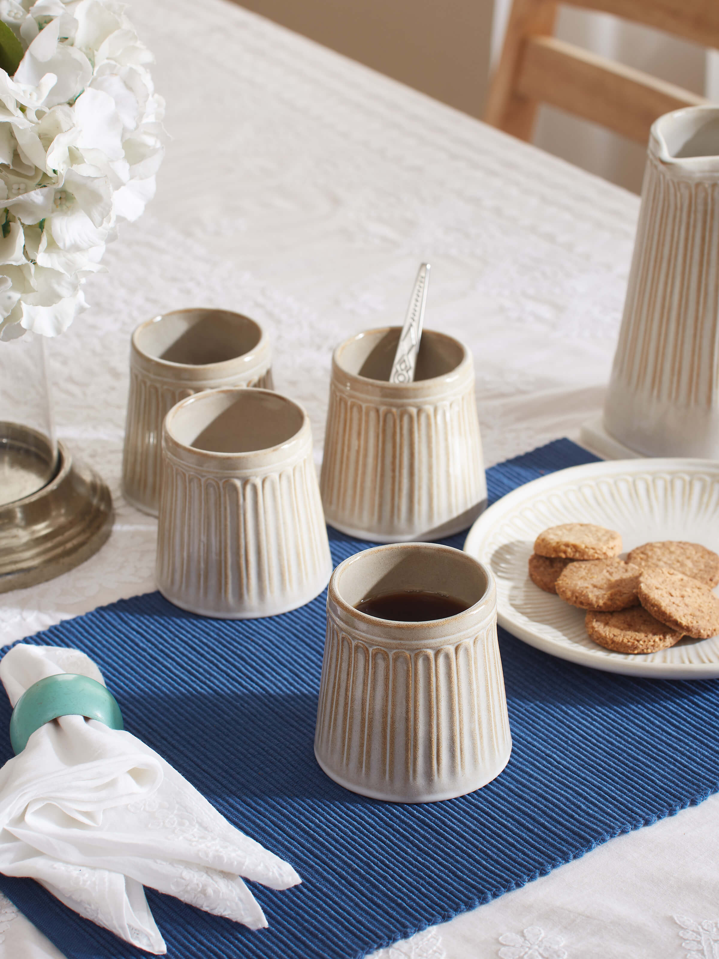 Close-up view of beige studio pottery ceramic water tumblers, highlighting their texture and color.