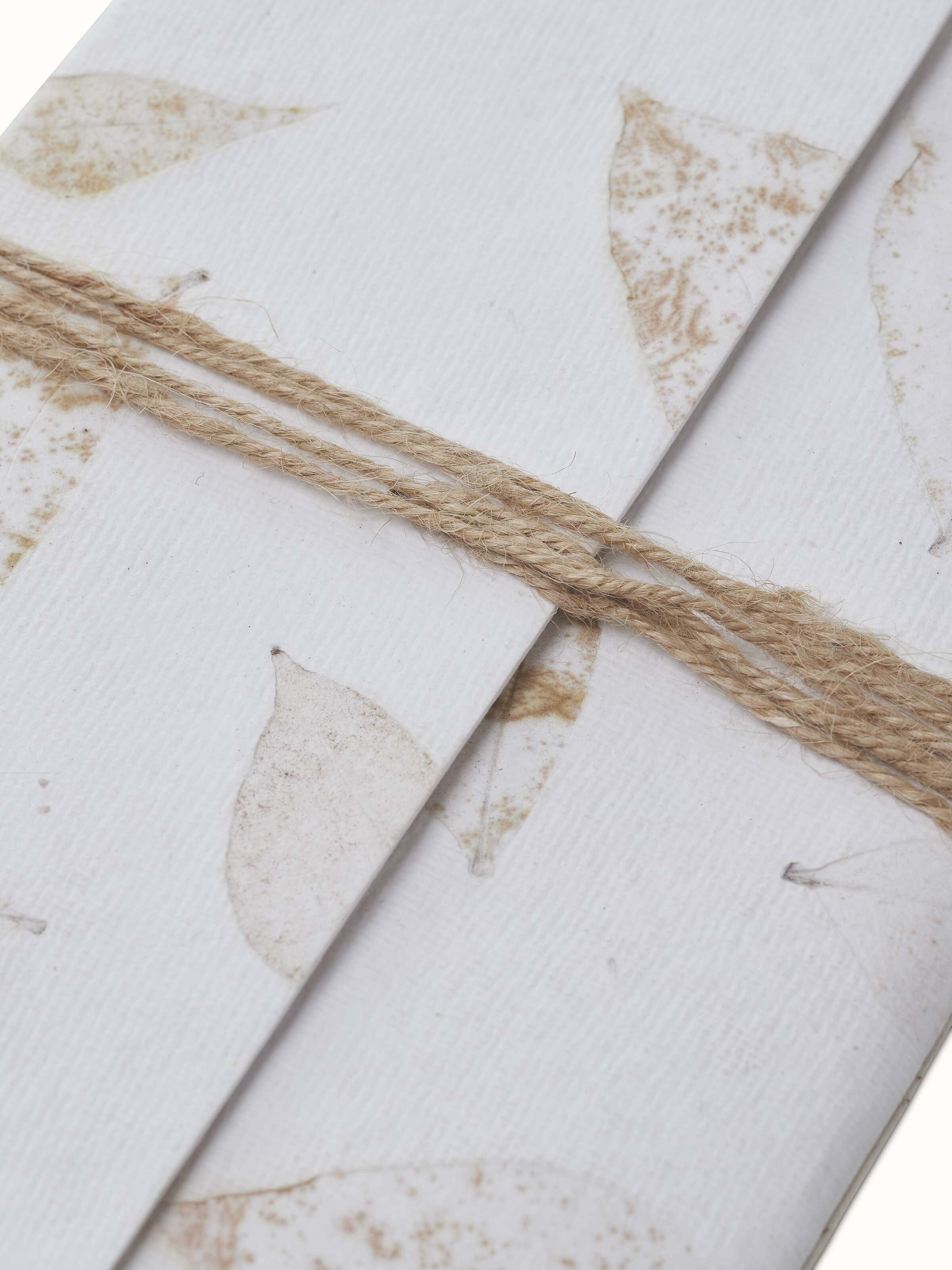 Angle view of Auroville Handmade Paper Notebook with Rope in white, showing the notebook's overall structure.