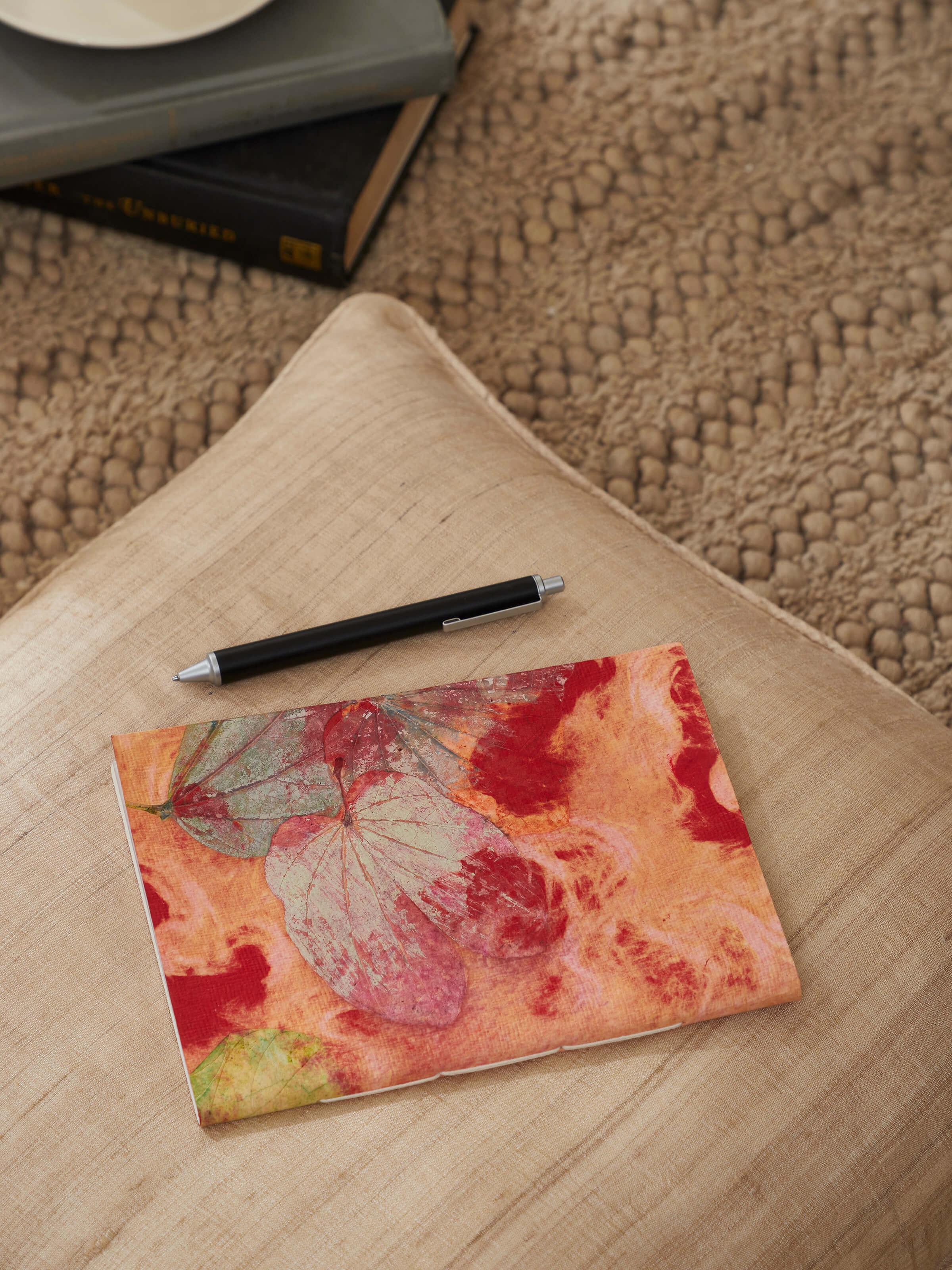 Side view of Auroville handmade paper notebook in orange showcasing its handcrafted binding and vibrant color.