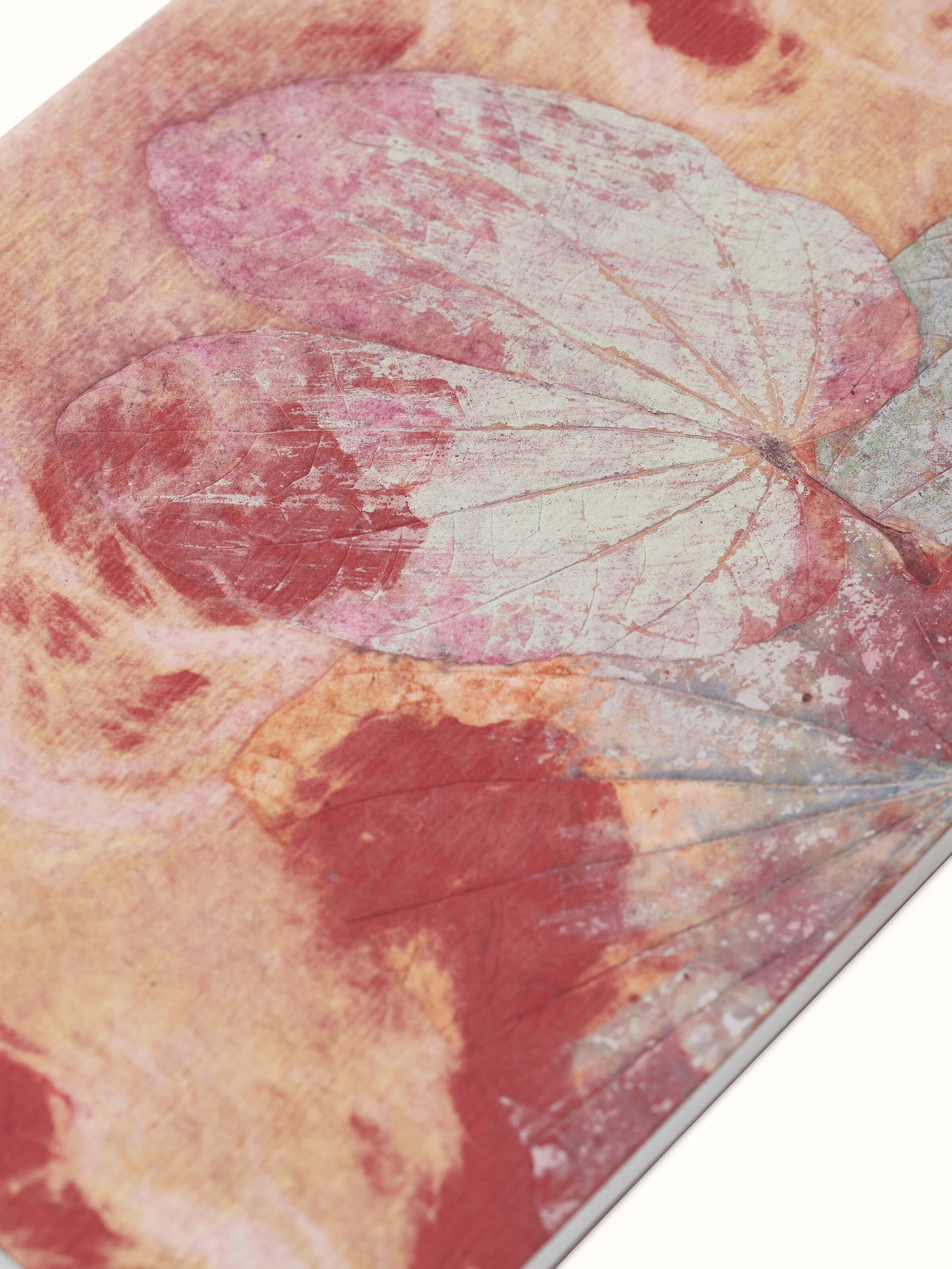 Angled view of Auroville handmade paper notebook in orange emphasizing its artisanal craftsmanship and page texture.