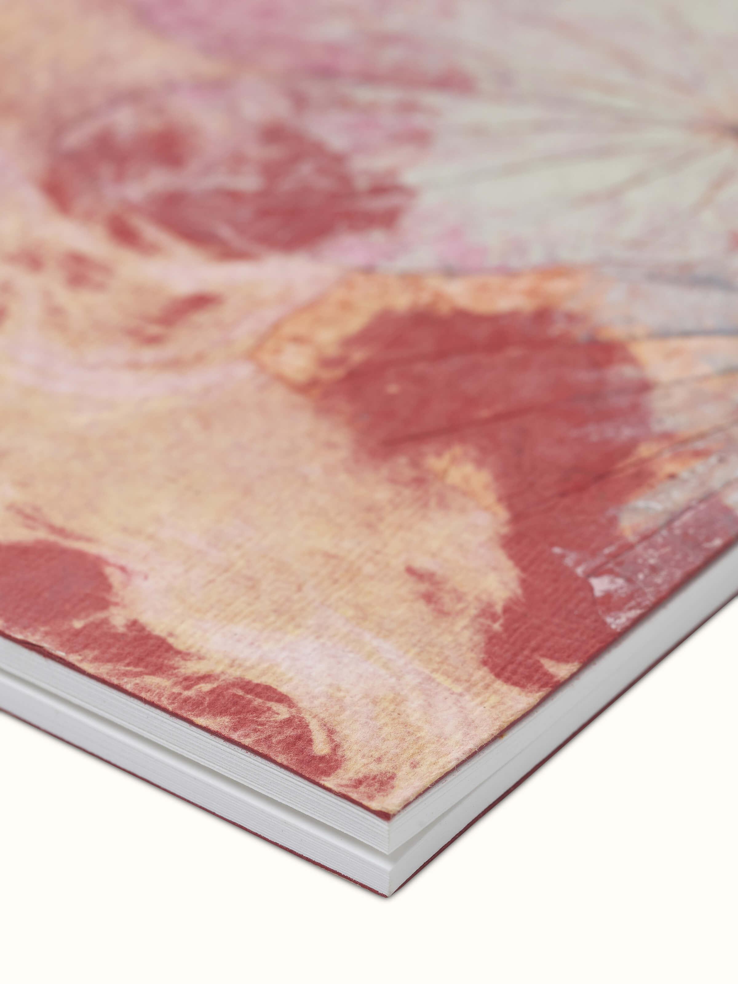 Close-up view of Auroville handmade paper notebook in orange focusing on the handmade paper quality and design details.