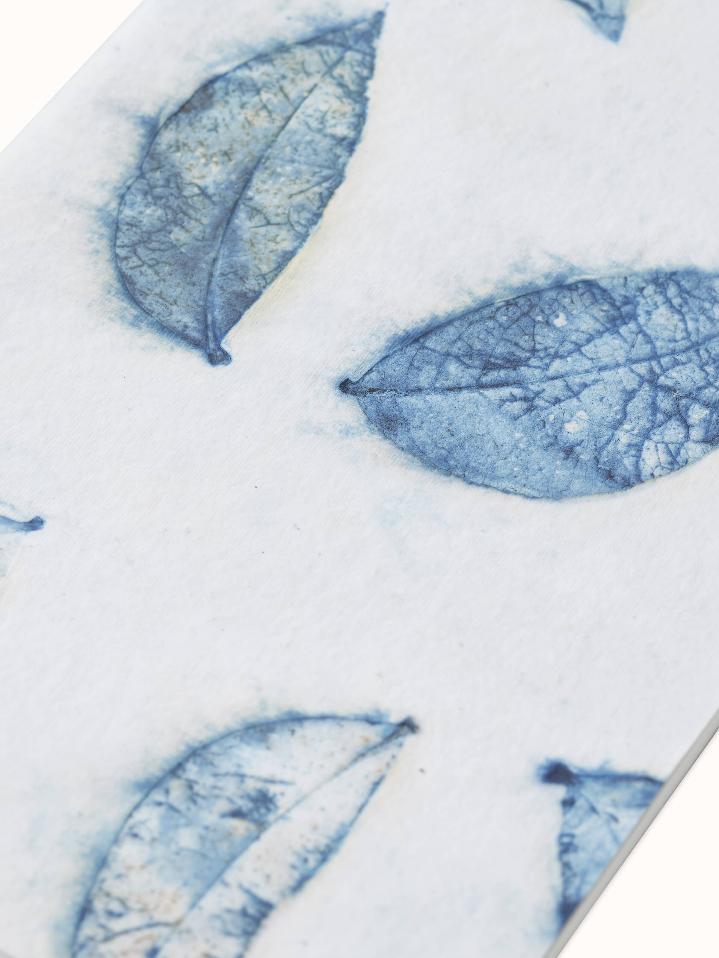 Angled view of Auroville handmade paper notebook in blue, emphasizing the unique texture and design of the pages.