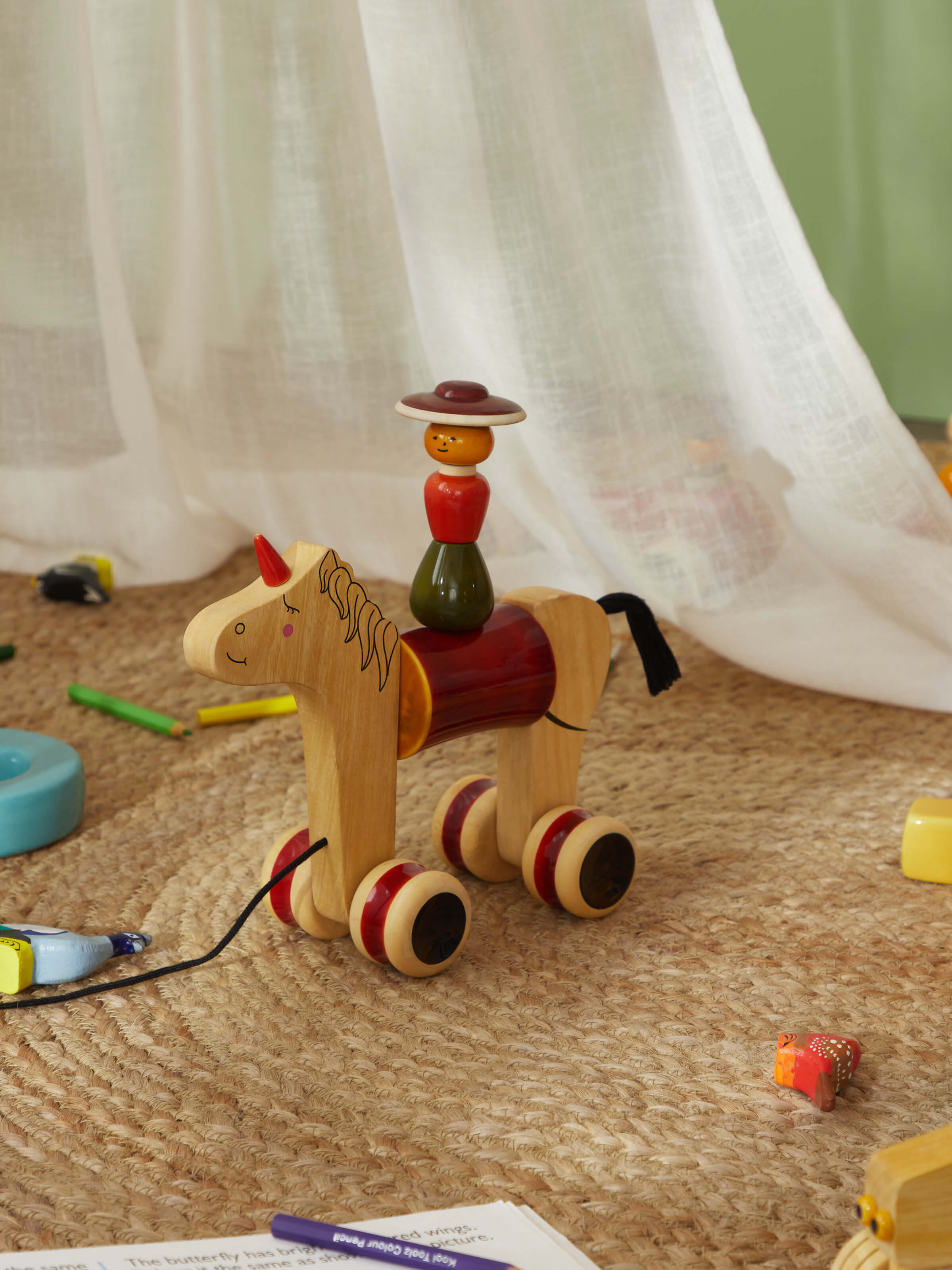 Side view of Channapatna Ivory Wood Woman Rider Hee Haw in red showing the design and wooden details.