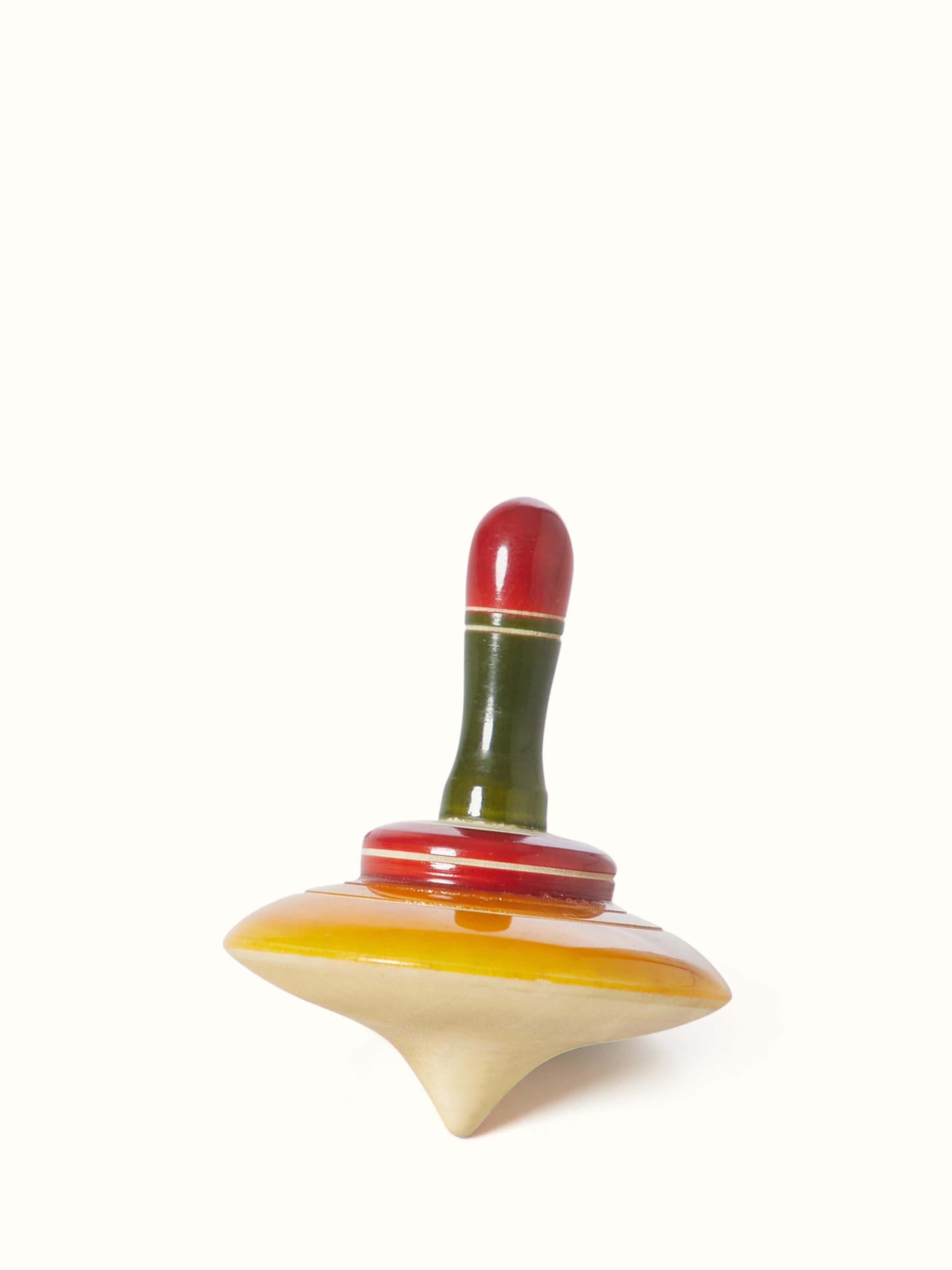 Angled view of Channapatna ivory wood merry top with detailed carving.