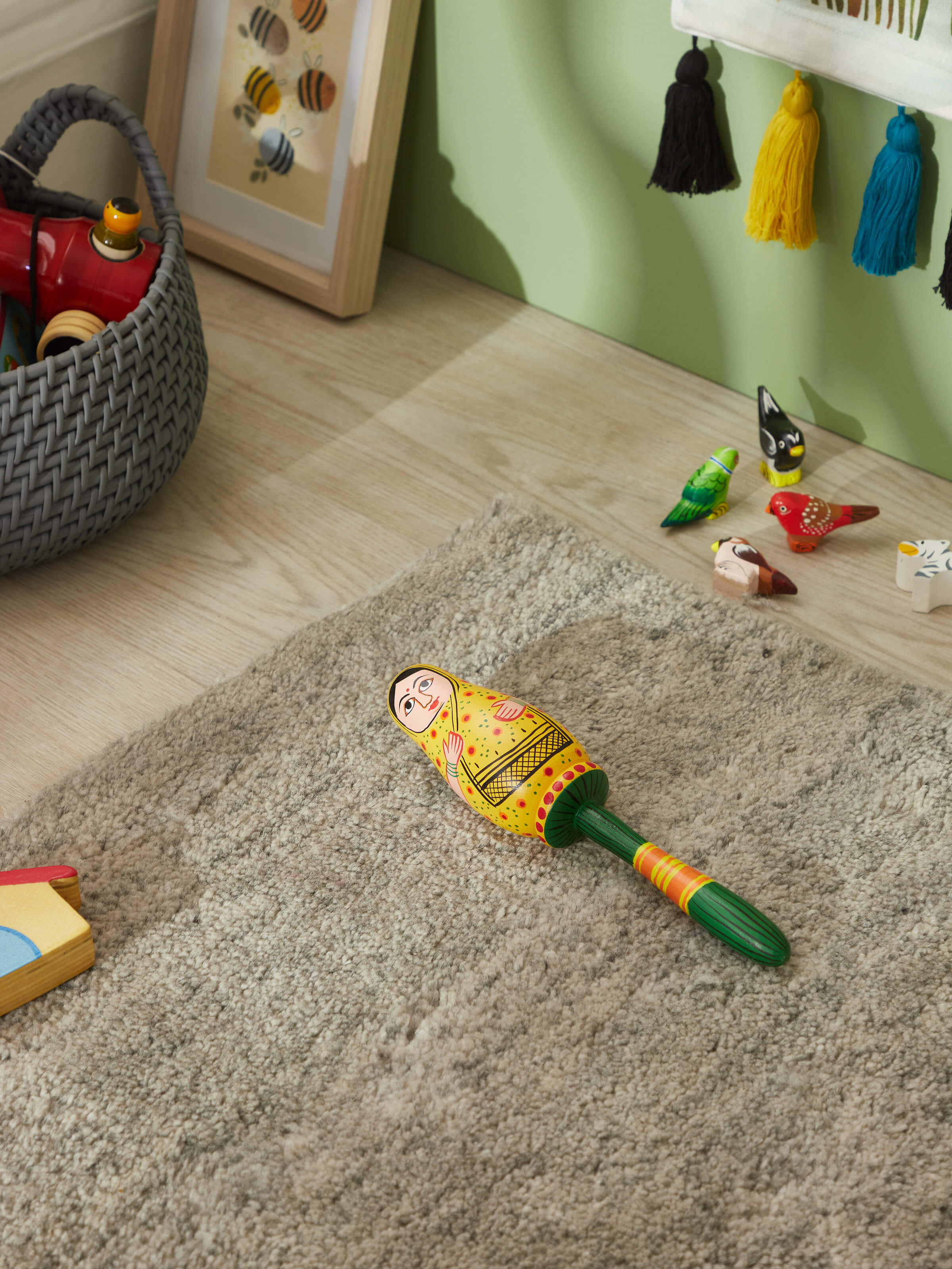 Side view of Wooden lady rattle toy in yellow highlighting the detailed craftsmanship and smooth finish