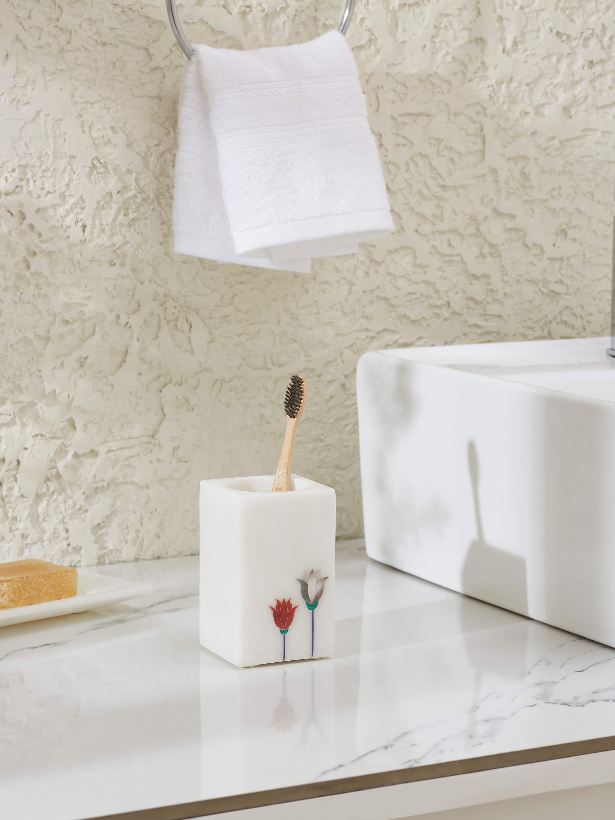 Side view of Carved Ambaji white marble floral toothbrush holder highlighting intricate floral patterns.