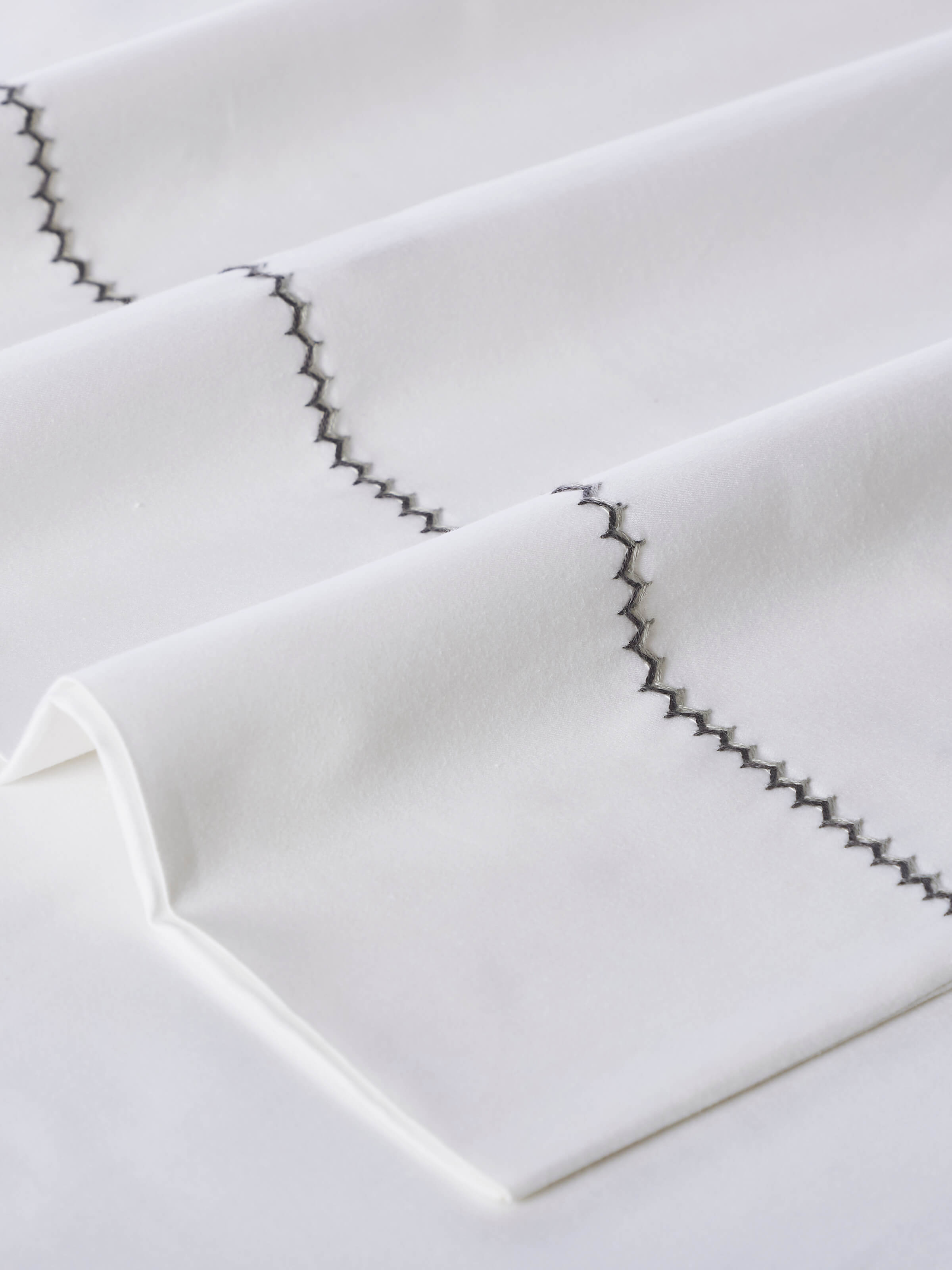 Rambagh grey stripe cotton hand embroidered bedsheet king set in a bedroom setting, displaying its design and application.