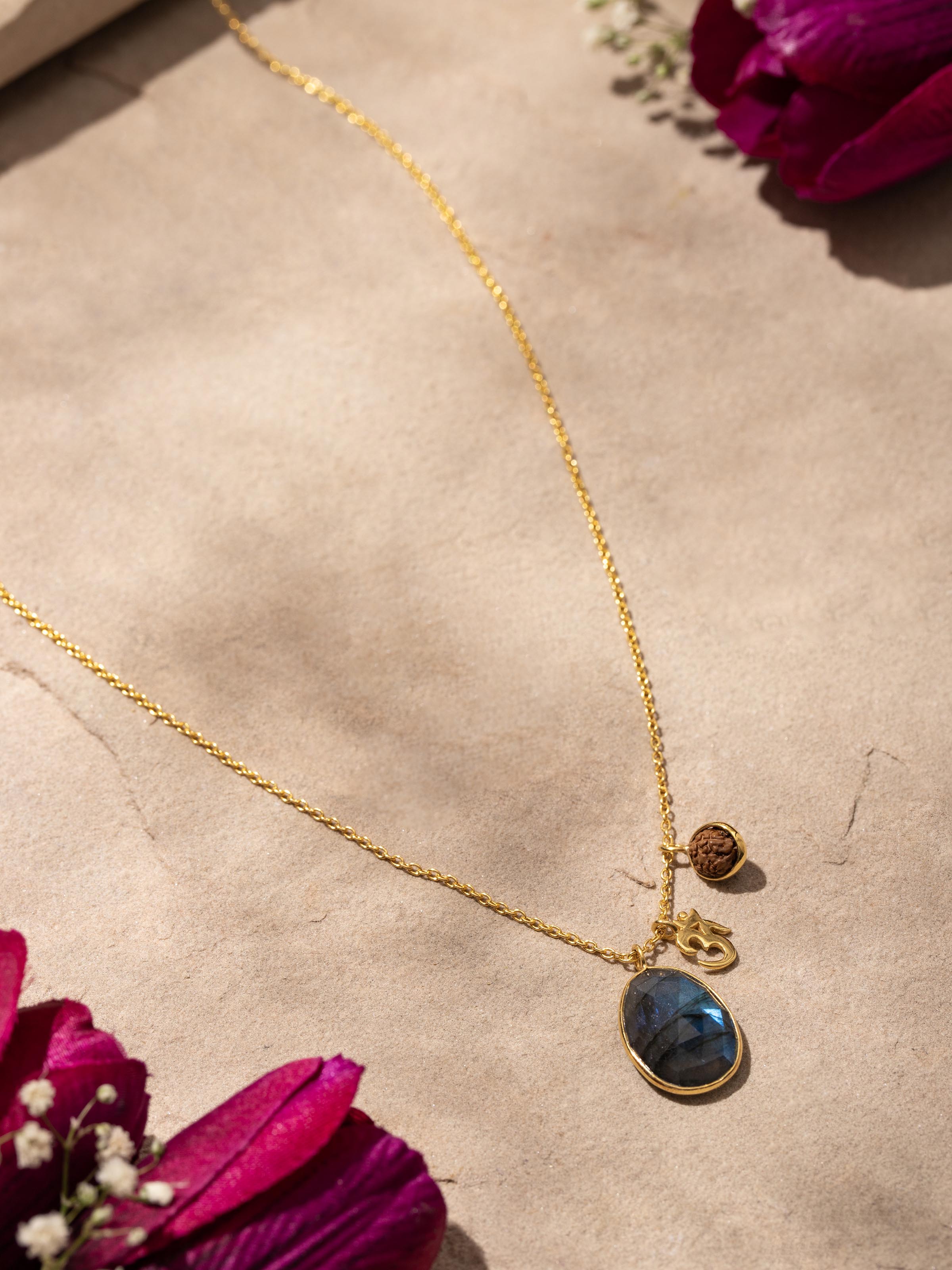 Close-up of Labradorite, OM silver charm & Rudraksha necklace showcasing intricate details and 18K gold plating.