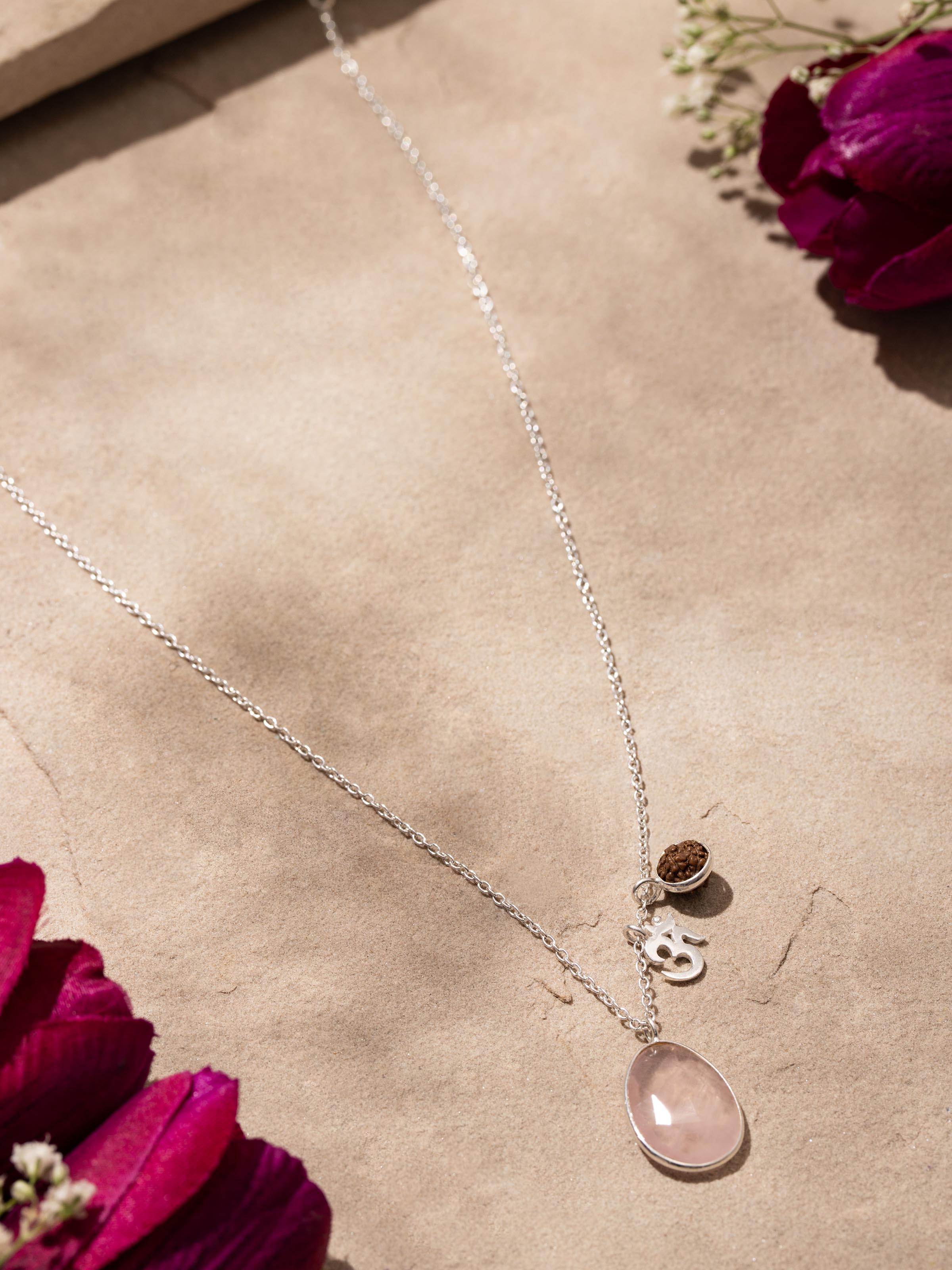 Side view of Rose Quartz, Om Silver Charm & Rudraksha Sterling Silver Necklace, highlighting the charm's placement on the chain.