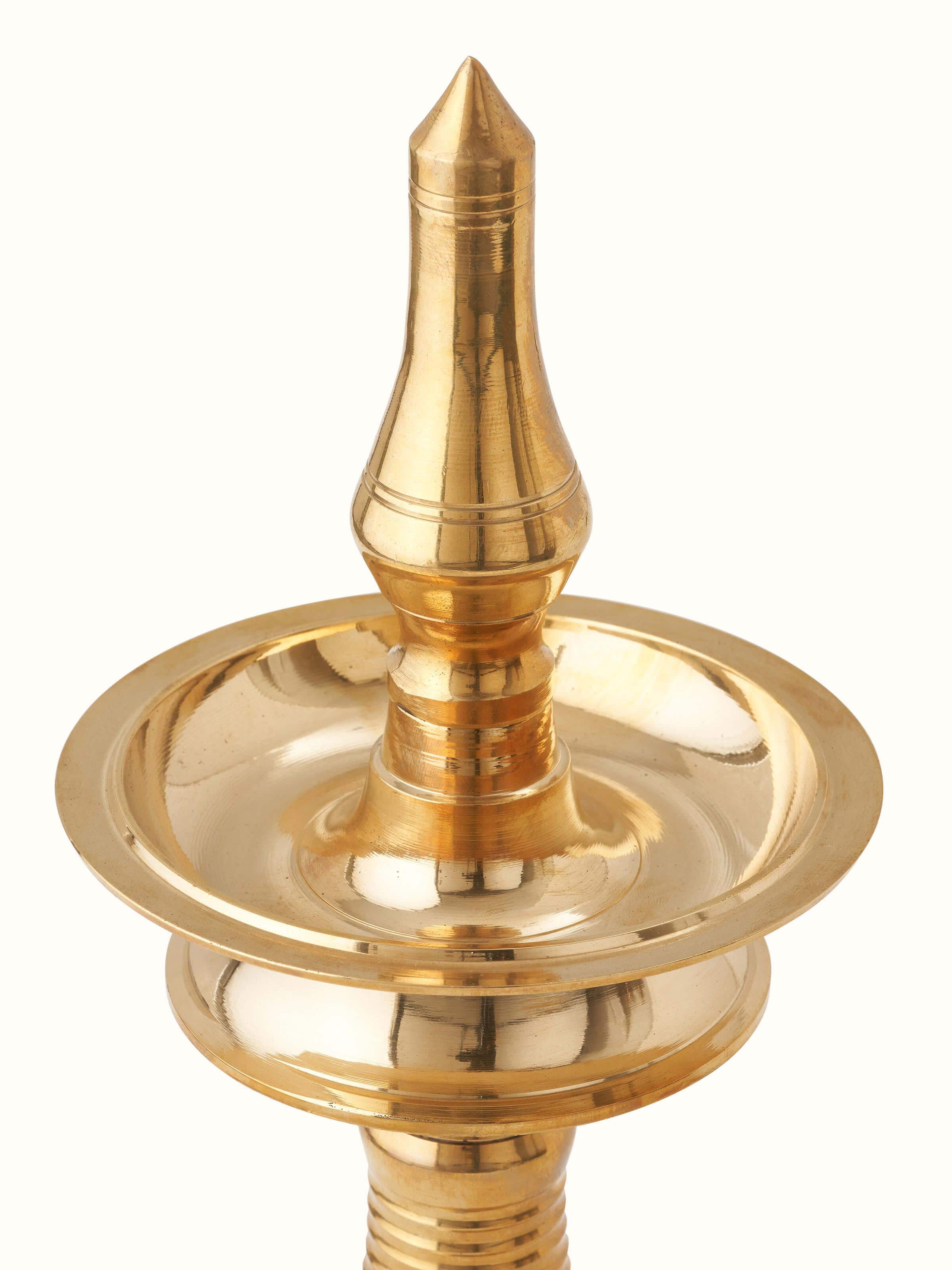 Angled view of brass kuthu vilakku stand diya, showcasing its decorative features and functional design.