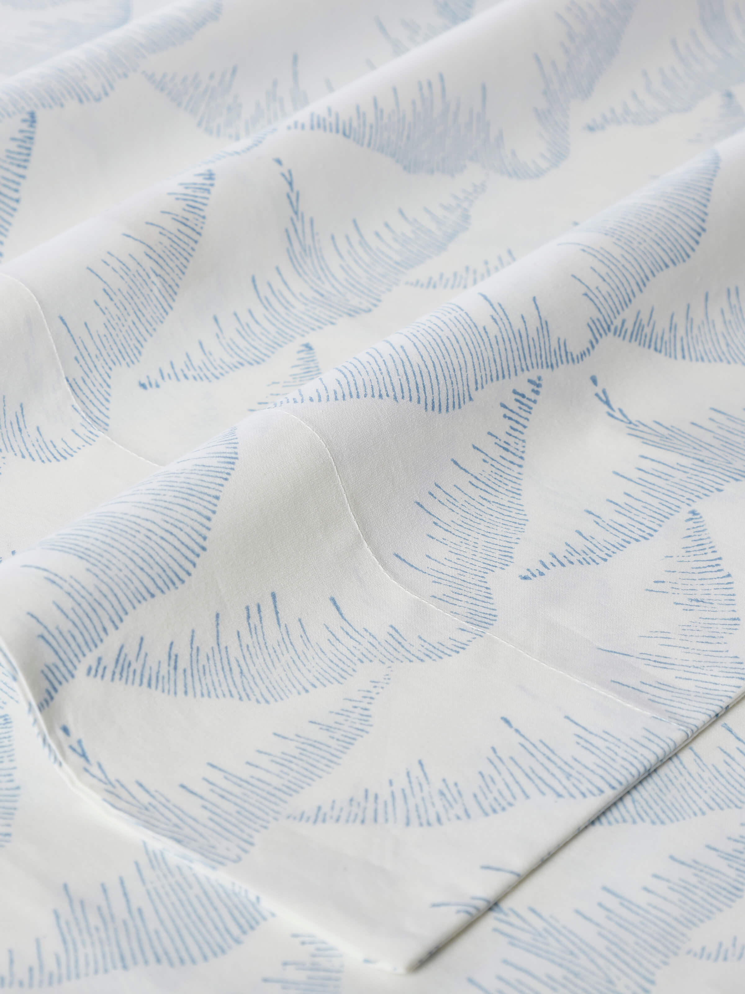 Angle view of Parvat Blue Textured Cotton Sanganeri Block Printed King Bedsheet Set (3 pcs) displaying the bedsheet and pillow covers.