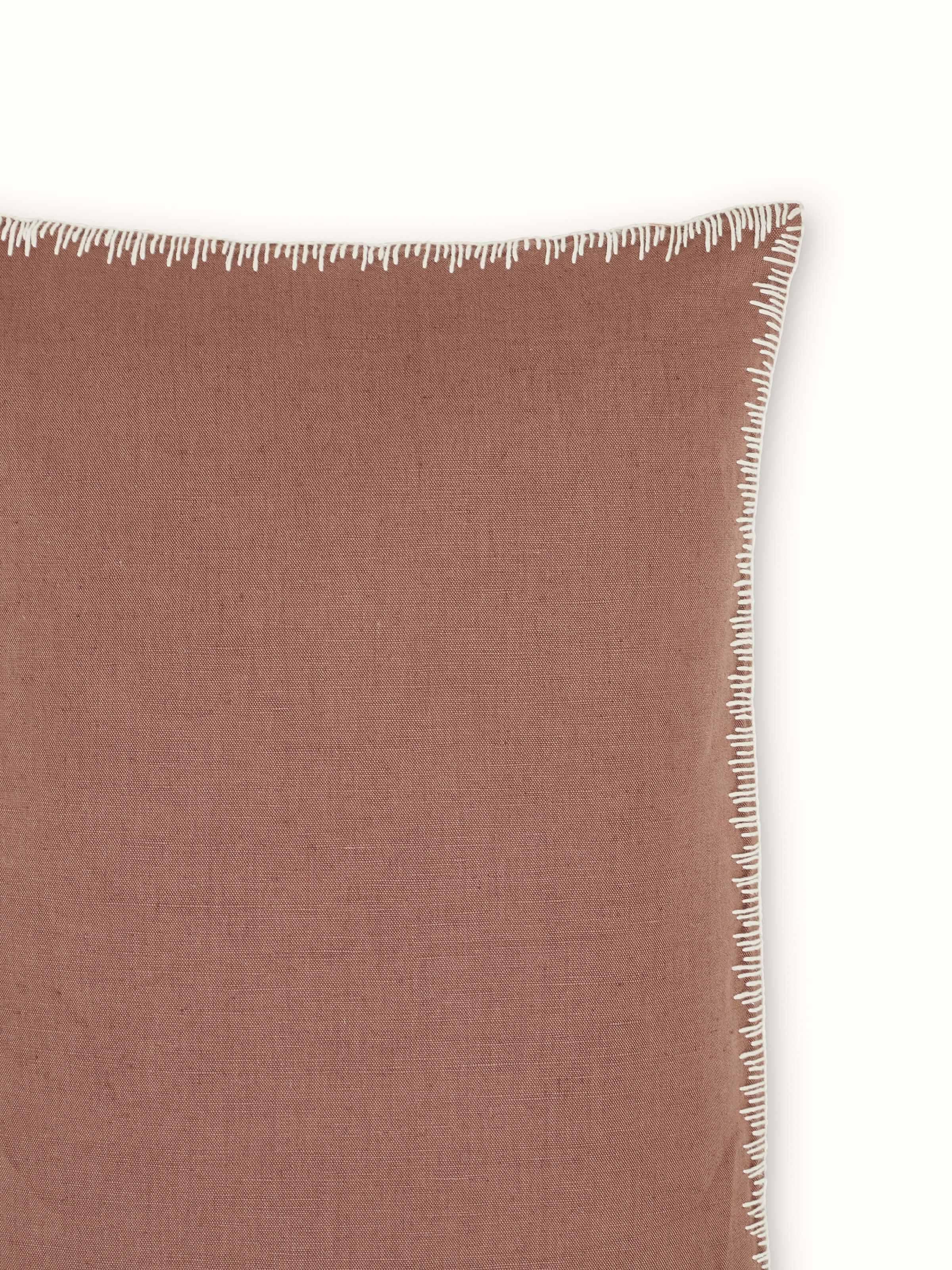 Side view of Parvat brown edge stitch linen cotton cushion cover with emphasis on embroidery and edge stitch