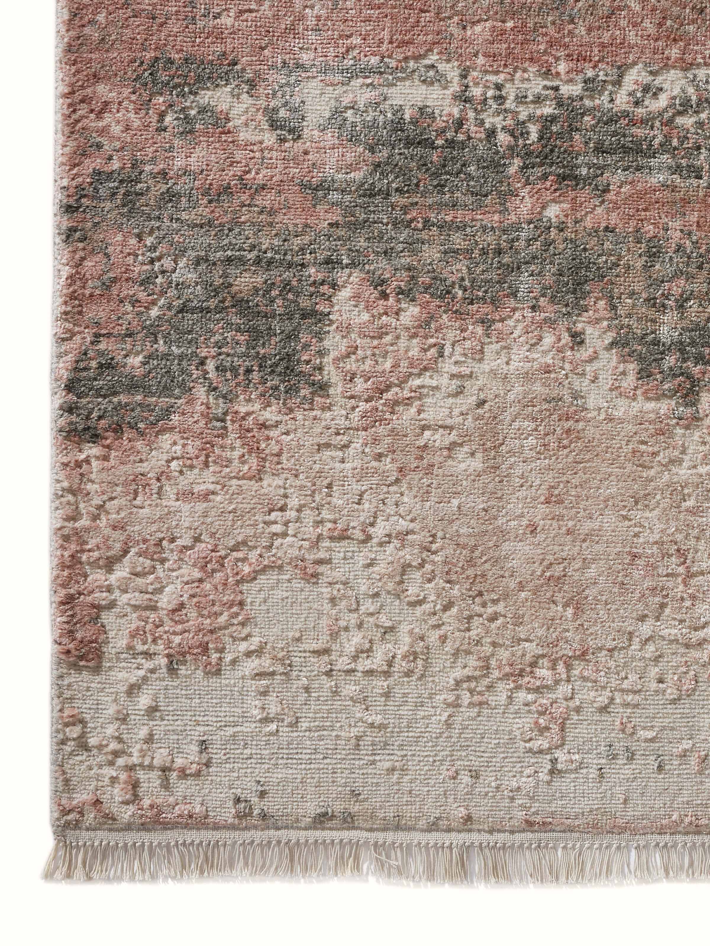 Detail shot of hand-knotted wool and viscose carpet showing abstract pattern in peach and grey.