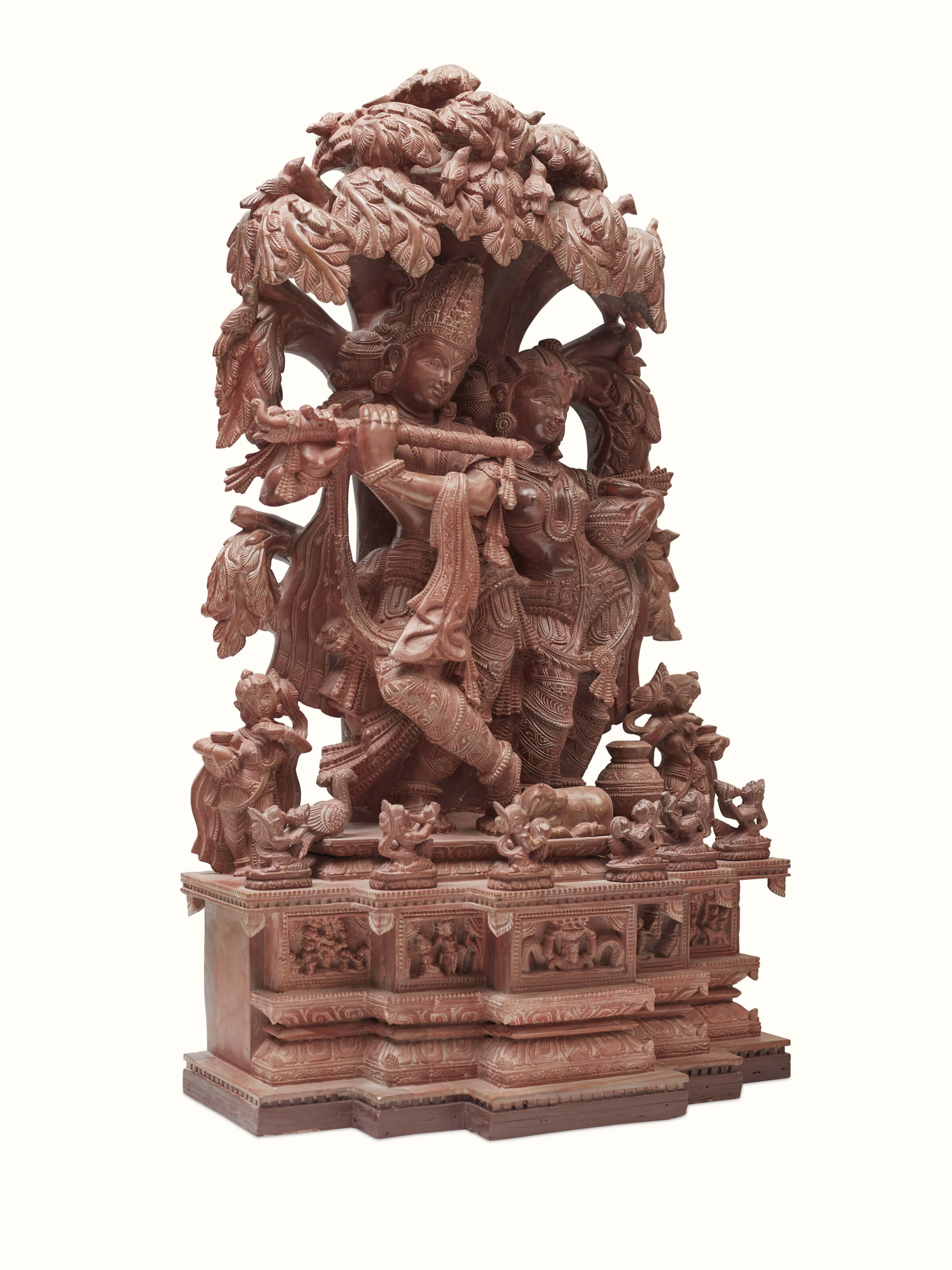 Angled view of the Radha & Krishna carved stone idol under the tree, highlighting intricate details.