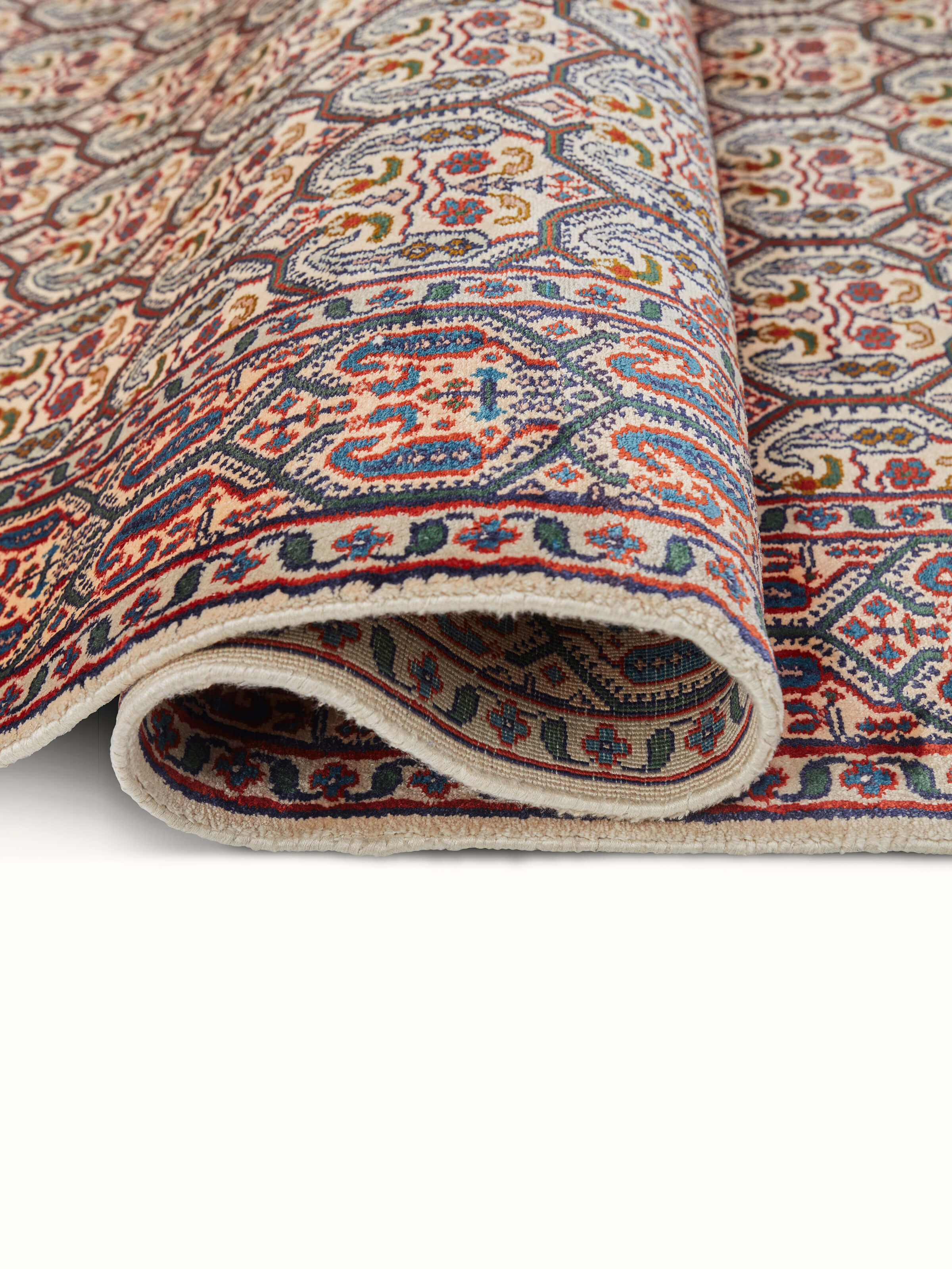 Close-up shot of the intricate patterns on a Persian silk hand-knotted carpet from Kashmir, emphasizing the fine details and vibrant colors.