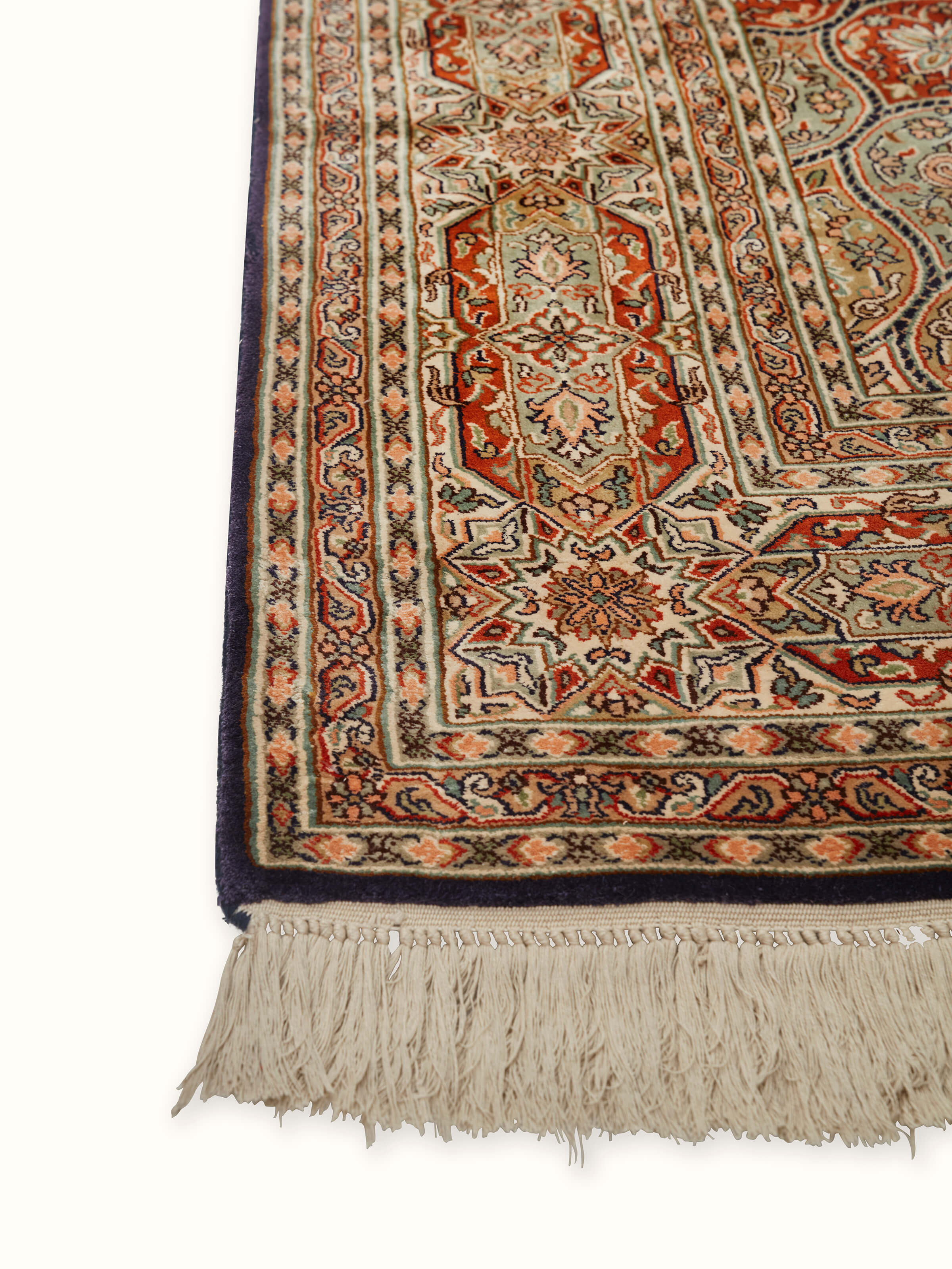 Close-up of Traditional Persian rust gumbad Kashmir silk hand-knotted carpet, emphasizing the intricate details and luxurious feel of the silk.