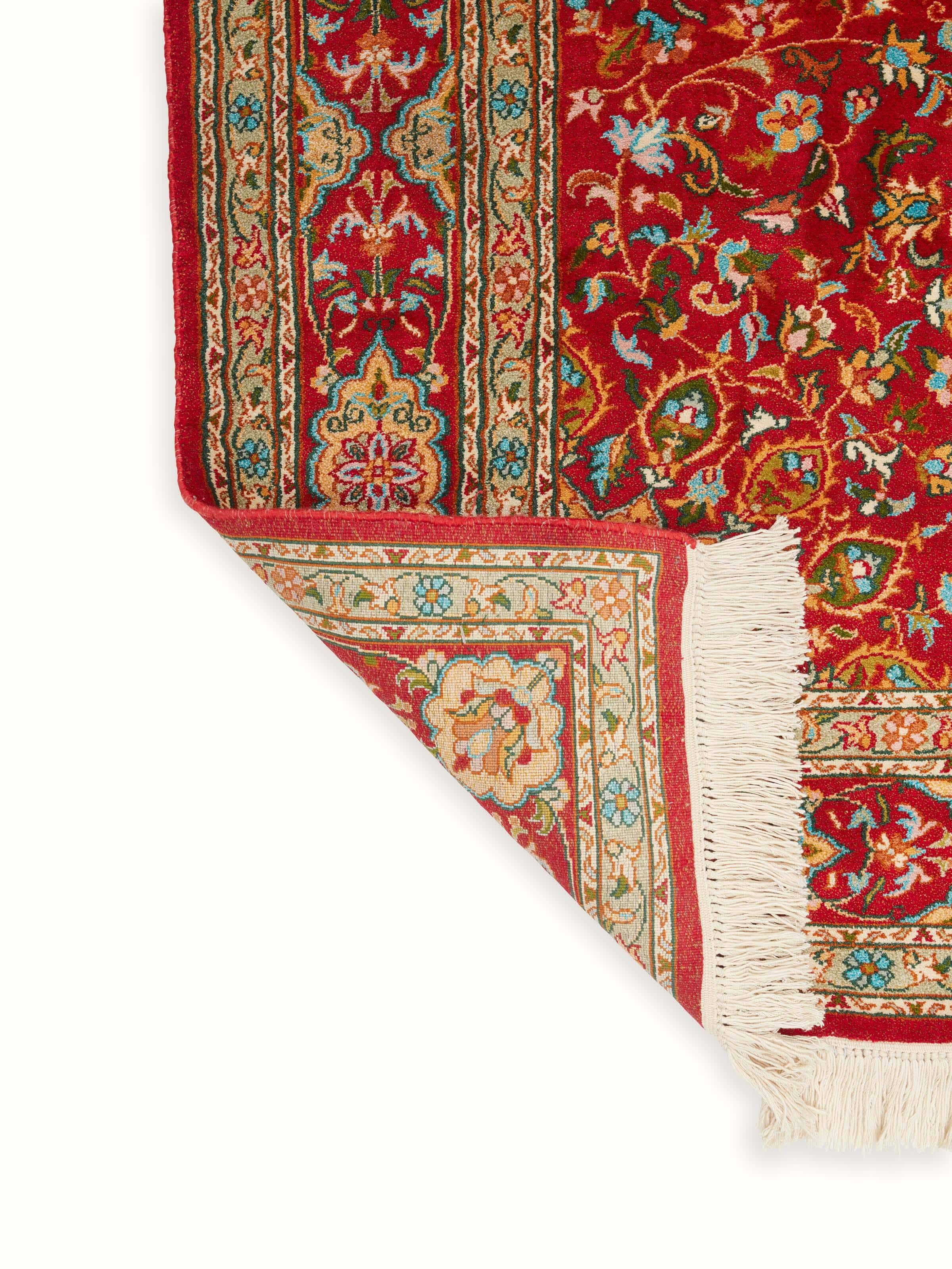 Traditional Persian red Kashan Kashmir silk hand-knotted runner folded to highlight its intricate patterns and silk quality.