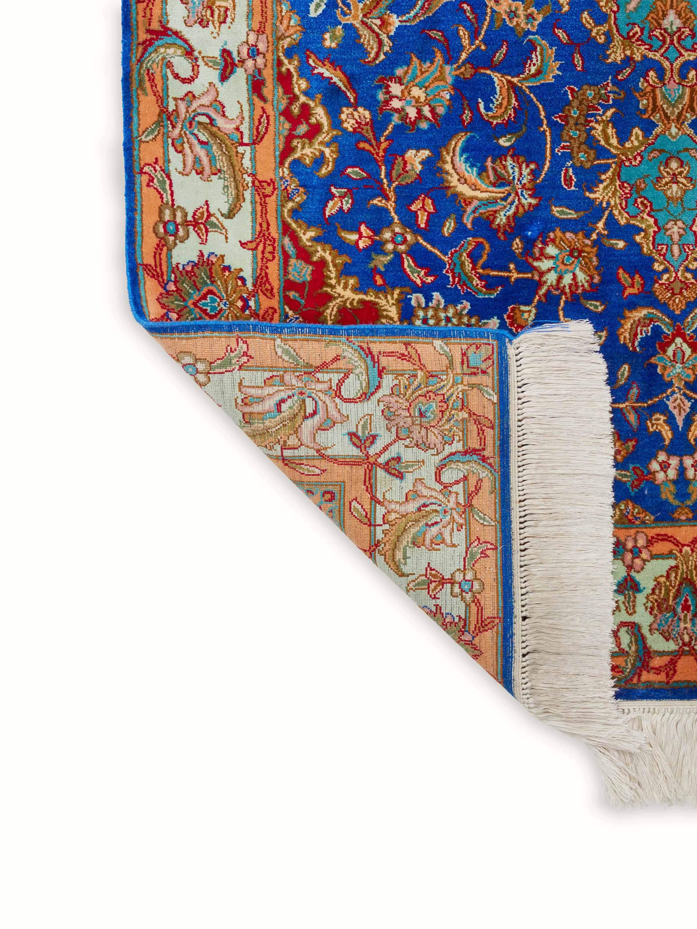 Full view of Traditional Persian Blue Red Kashan Kashmir silk hand-knotted carpet folded, emphasizing its design and silk texture.