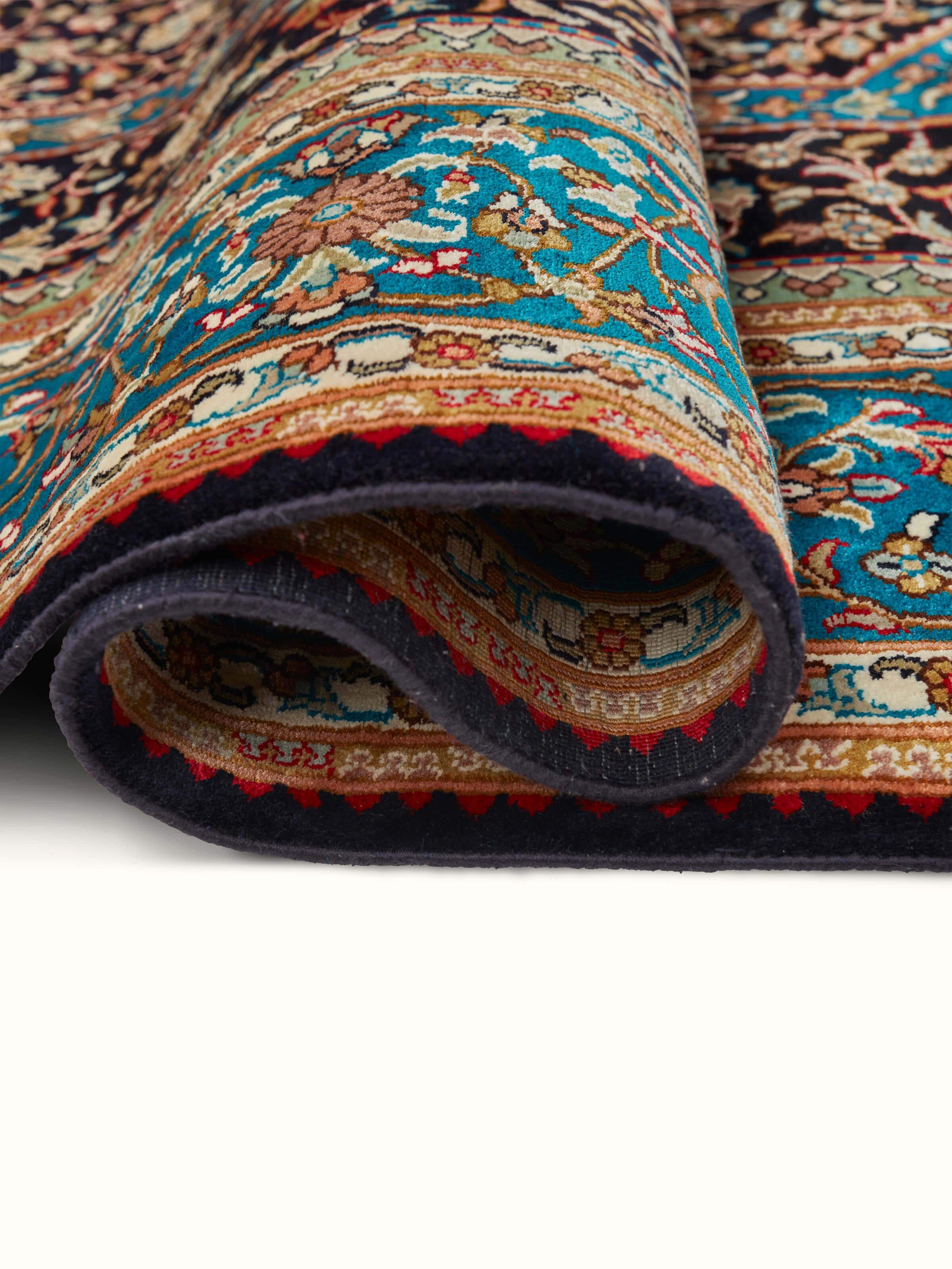 Close-up of Traditional Persian navy teal Kashan Kashmir silk hand-knotted carpet focusing on the texture and color details.