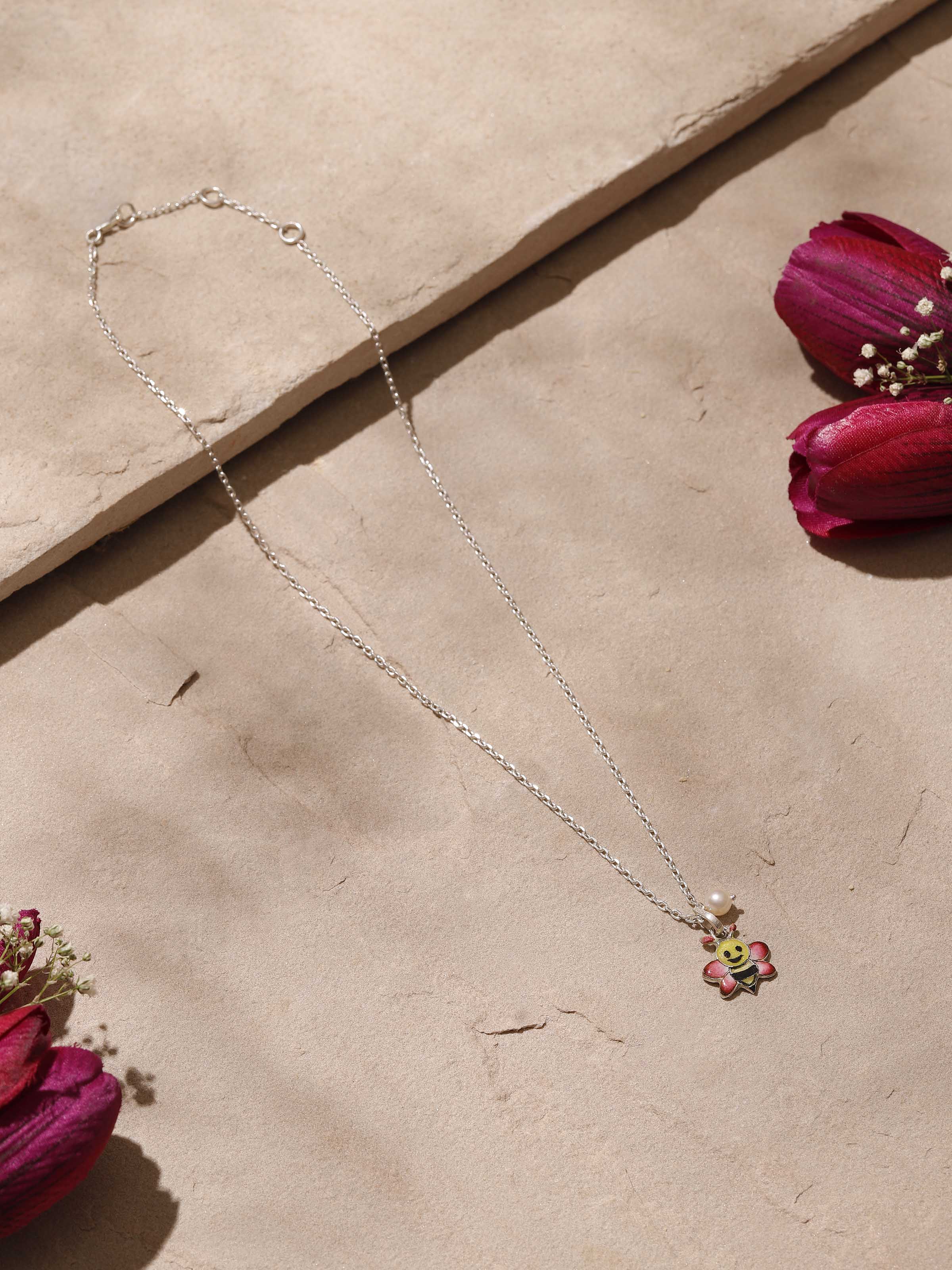 Close-up top view showing intricate pink meenakari patterns on the silver pendant
