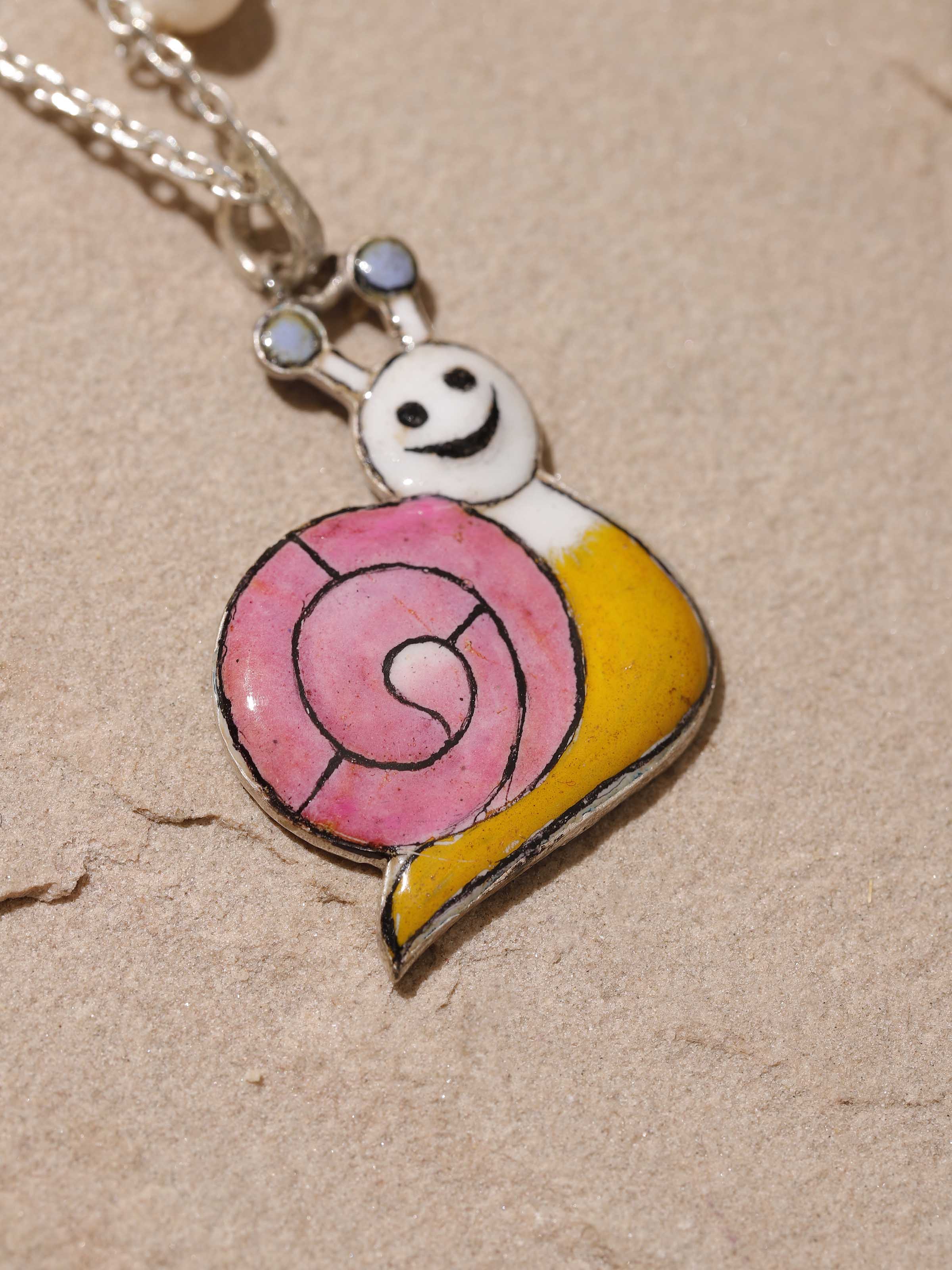 Side view highlighting the silver polish and vibrant enamel design of the pendant
