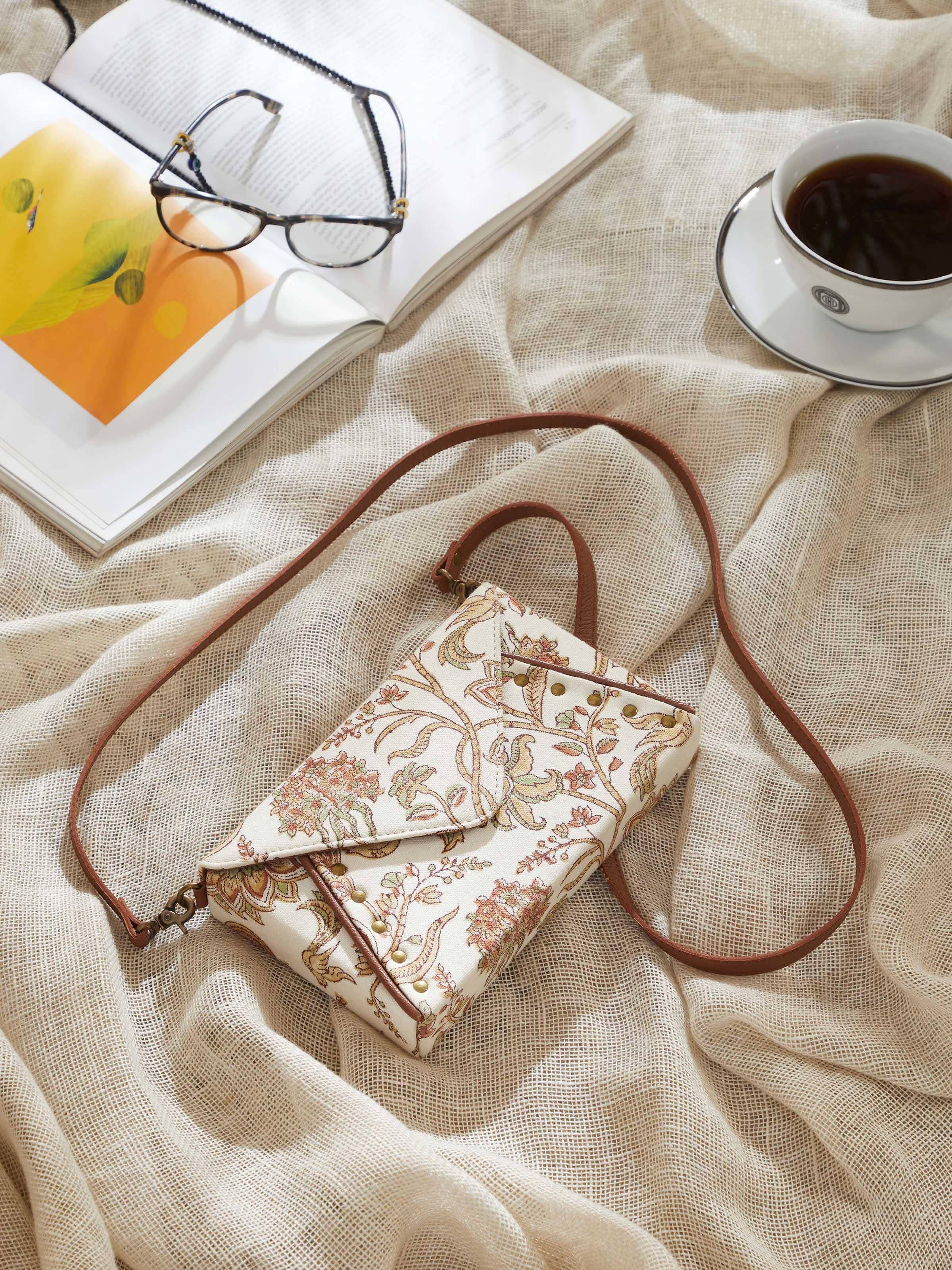 Lifestyle image of mustard sling bag worn crossbody, highlighting print and leather details