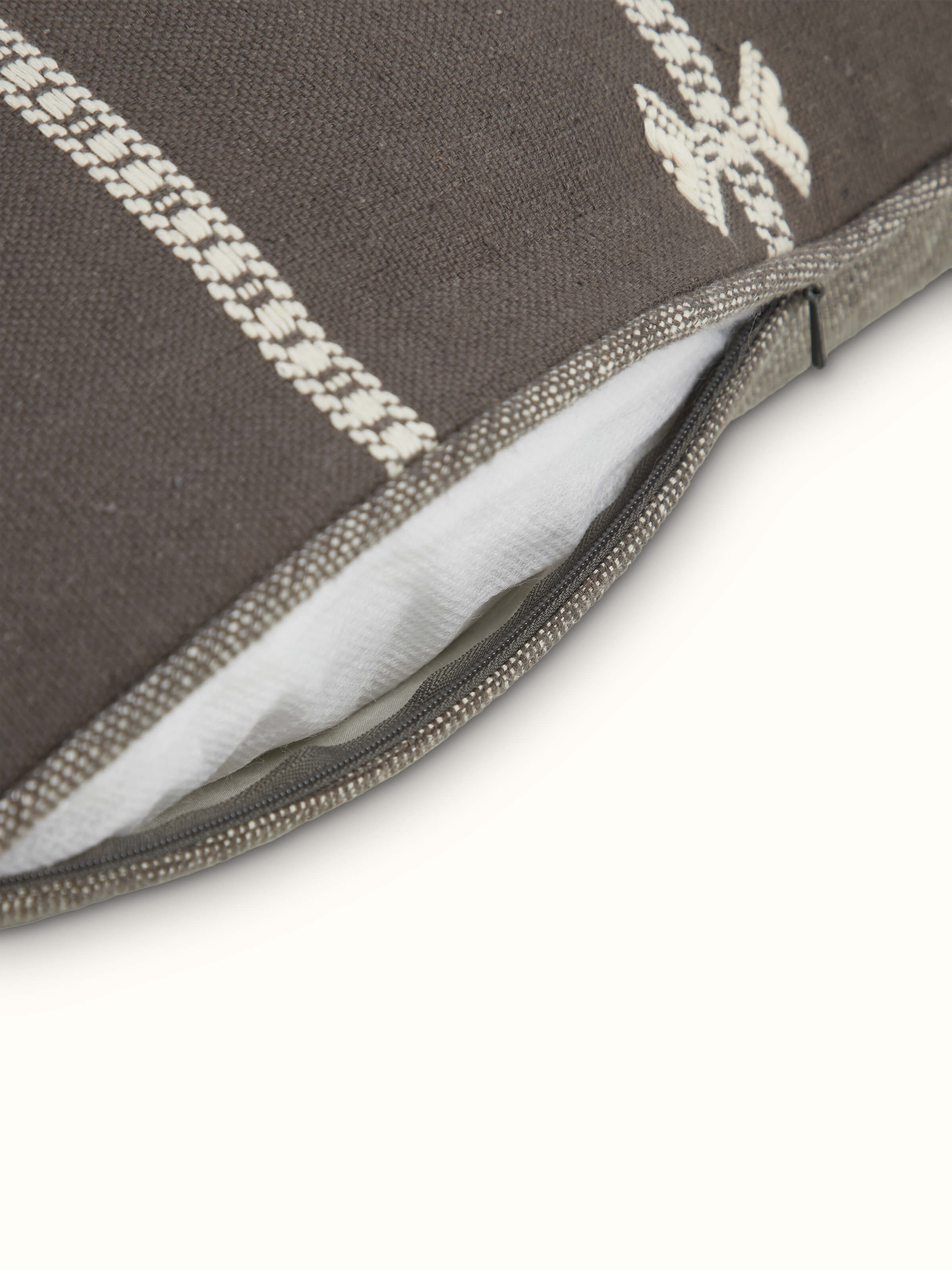 Angled view highlighting the textured weave and traditional Bhujodi pattern of the coffee-toned cushion cover