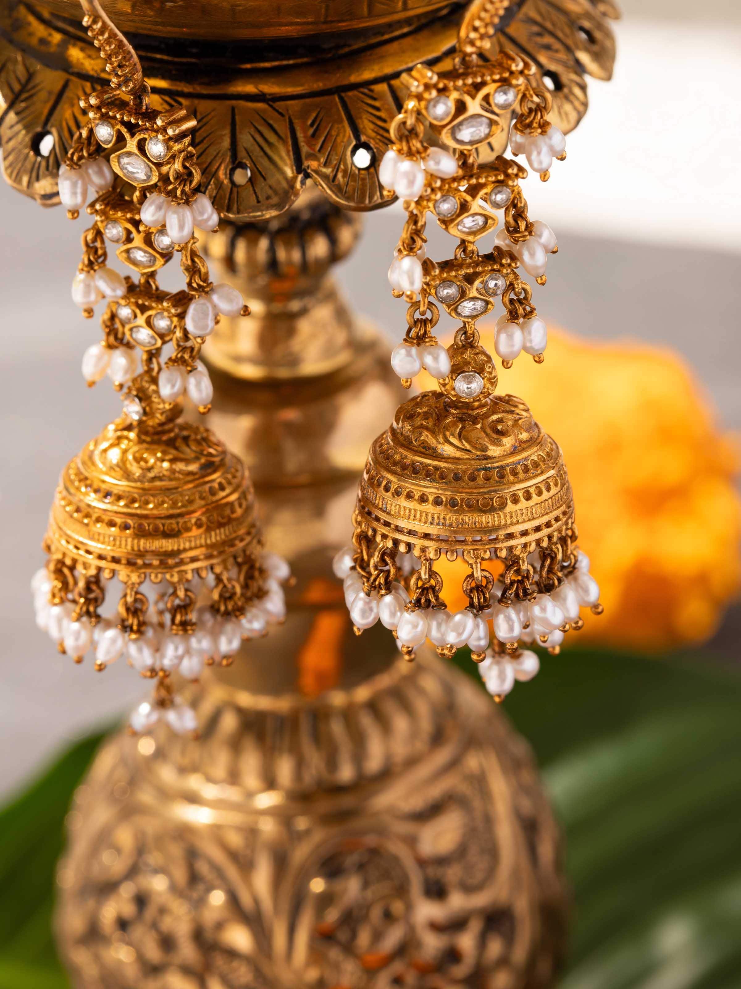 Close-up of silver Guttapusalu jhumkas in ear, highlighting pearls and filigree detailing.