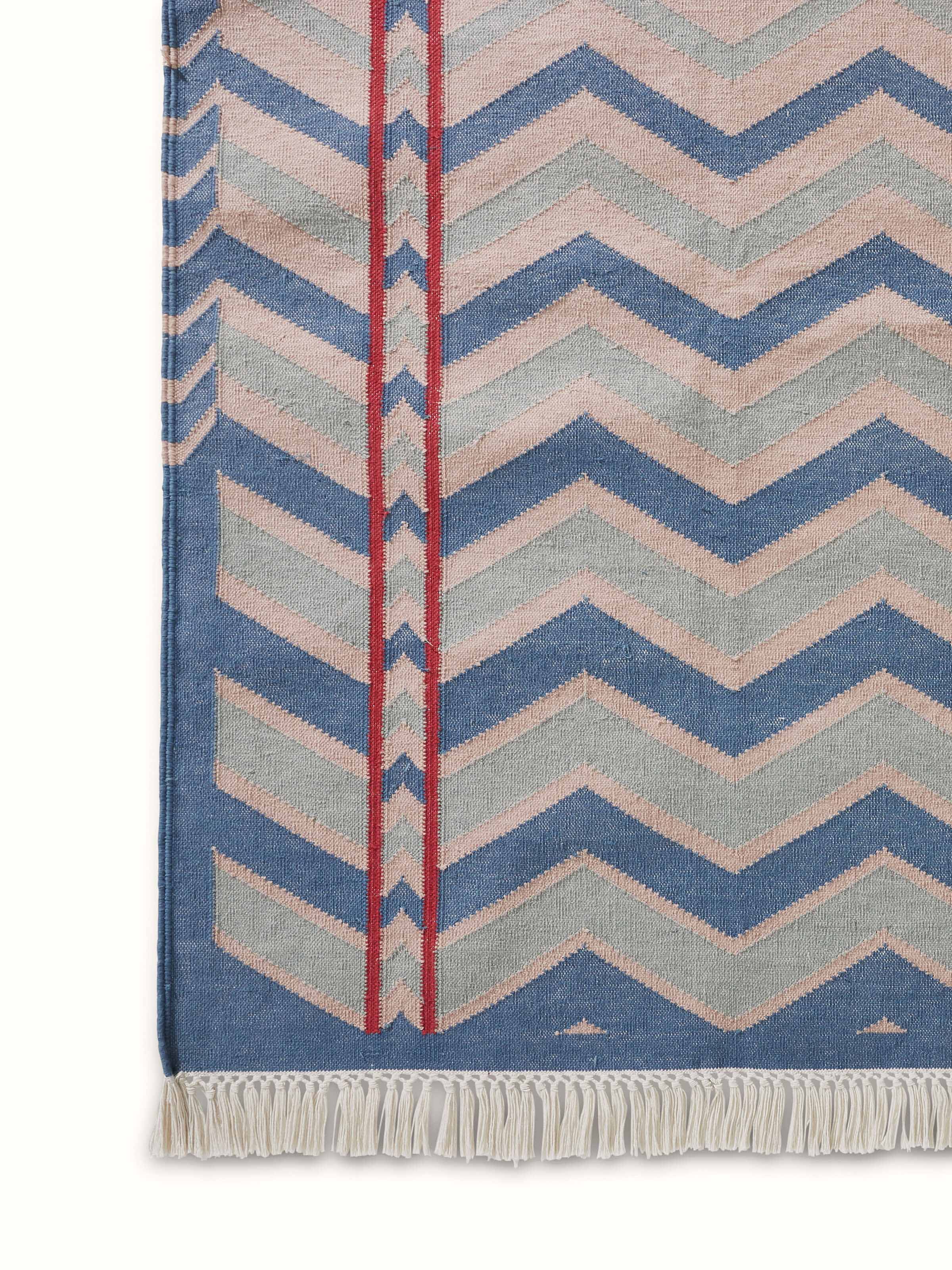 Angled view of Geo chevron gradation blue beige lawan cotton panja dhurrie demonstrating its design and usability.