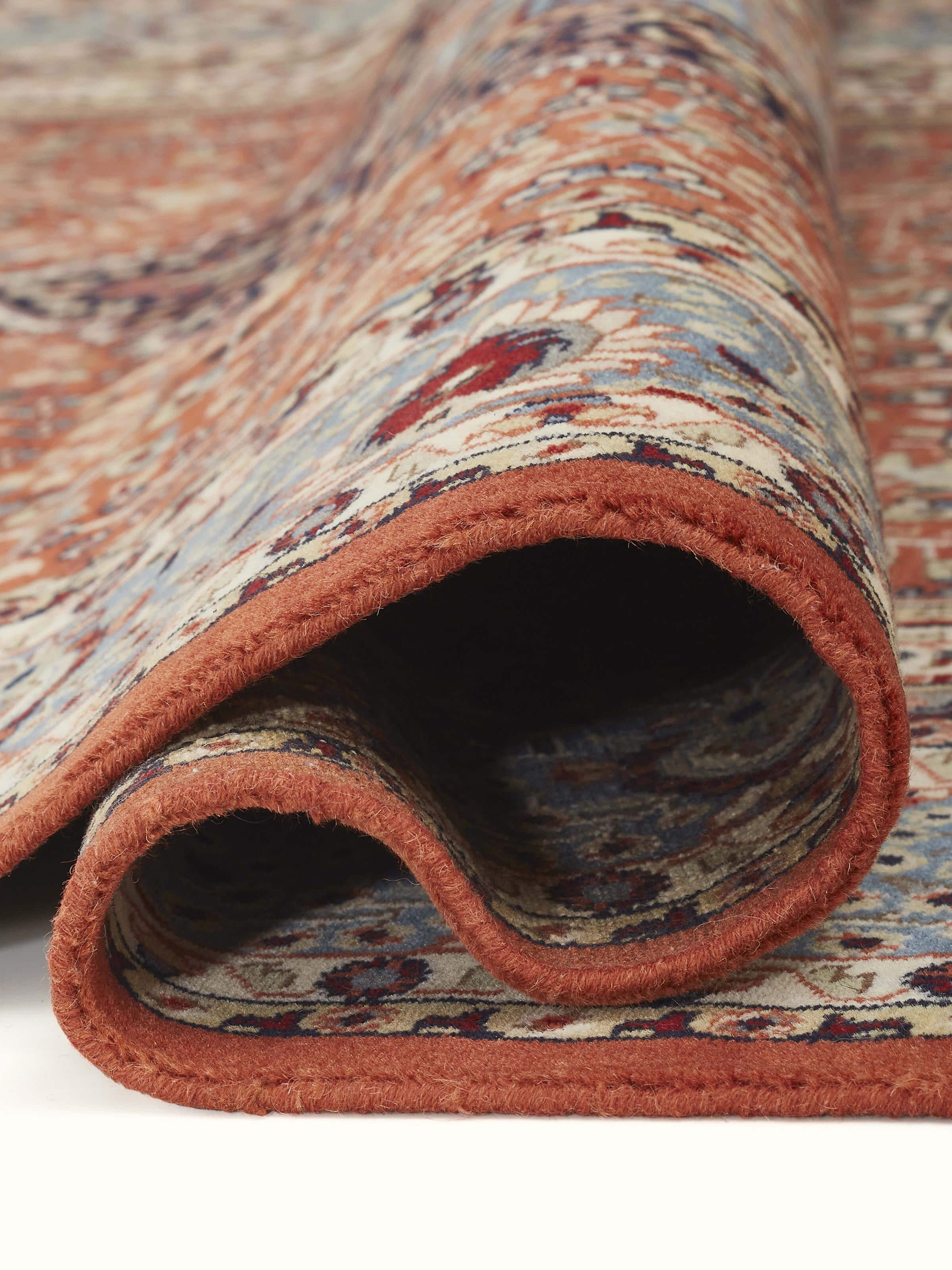 A corner detail of the rug reveals ornate borders and Persian-style floral patterns.