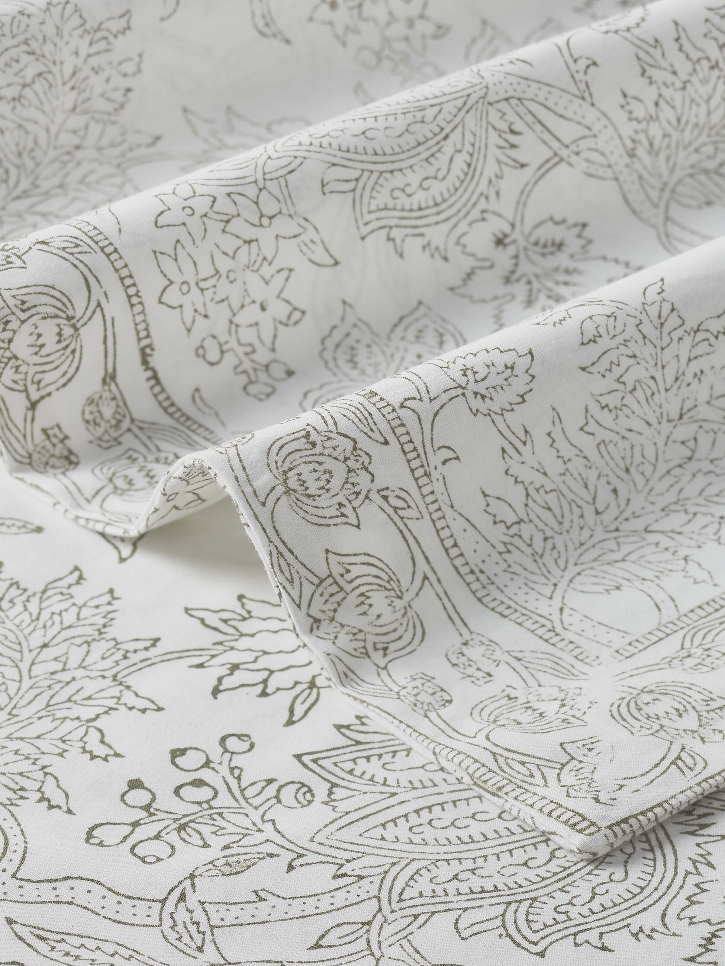 Detail shot of floral hand block print pattern on grey cotton bedsheet fabric